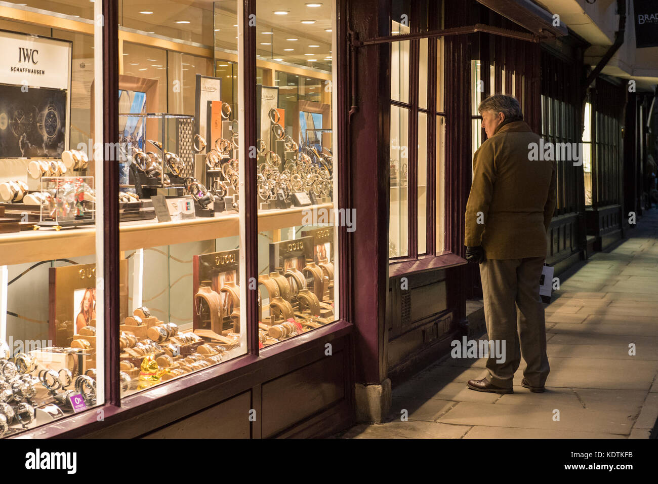 Winterabend im Zentrum von York, Mann ist auf der Suche nach Uhren Leuchten & in smart Juweliere Schaufenster - Stonegate, England, UK. Stockfoto