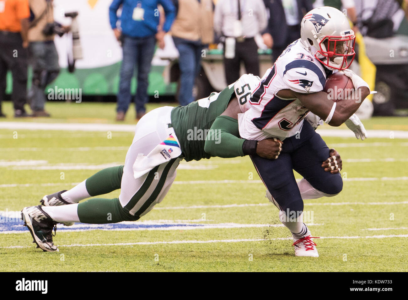 East Rutherford, New Jersey, USA. 15 Okt, 2017. New England Patriots zurück laufen Dion Lewis (33) läuft mit dem Ball wie New York Jets linebacker Demario Davis (56) versucht, ihn während der NFL Spiel zwischen den New England Patriots und die New York Jets an MetLife Stadium in East Rutherford, New Jersey in Angriff zu nehmen. Die New England Patriots gewannen 24-17. Christopher Szagola/CSM/Alamy leben Nachrichten Stockfoto