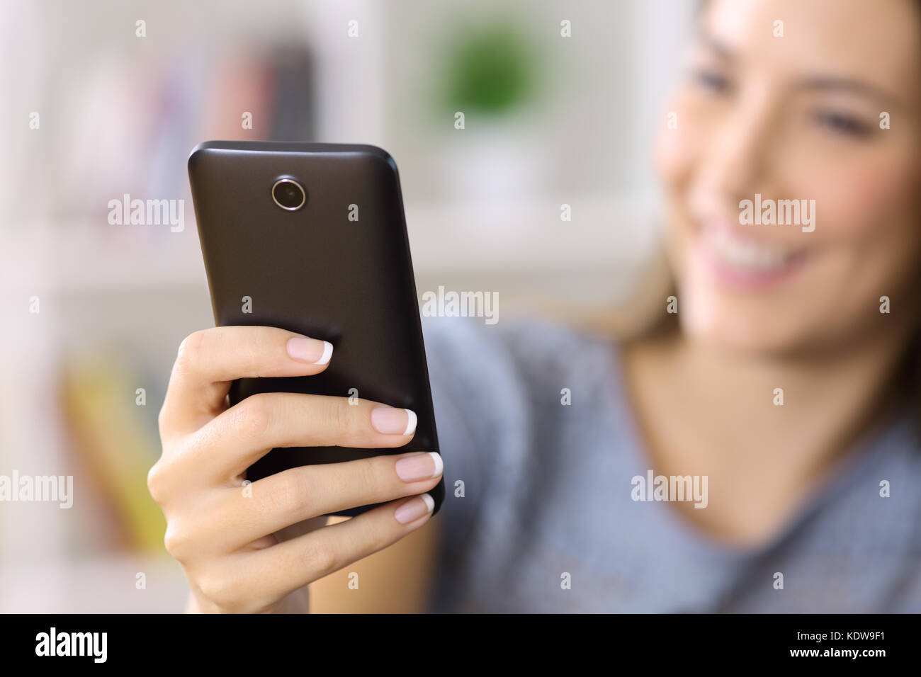 Nahaufnahme einer Frau hand mit einem smart phone mit ein unscharfes Gesicht und Hintergrund zu Hause Stockfoto