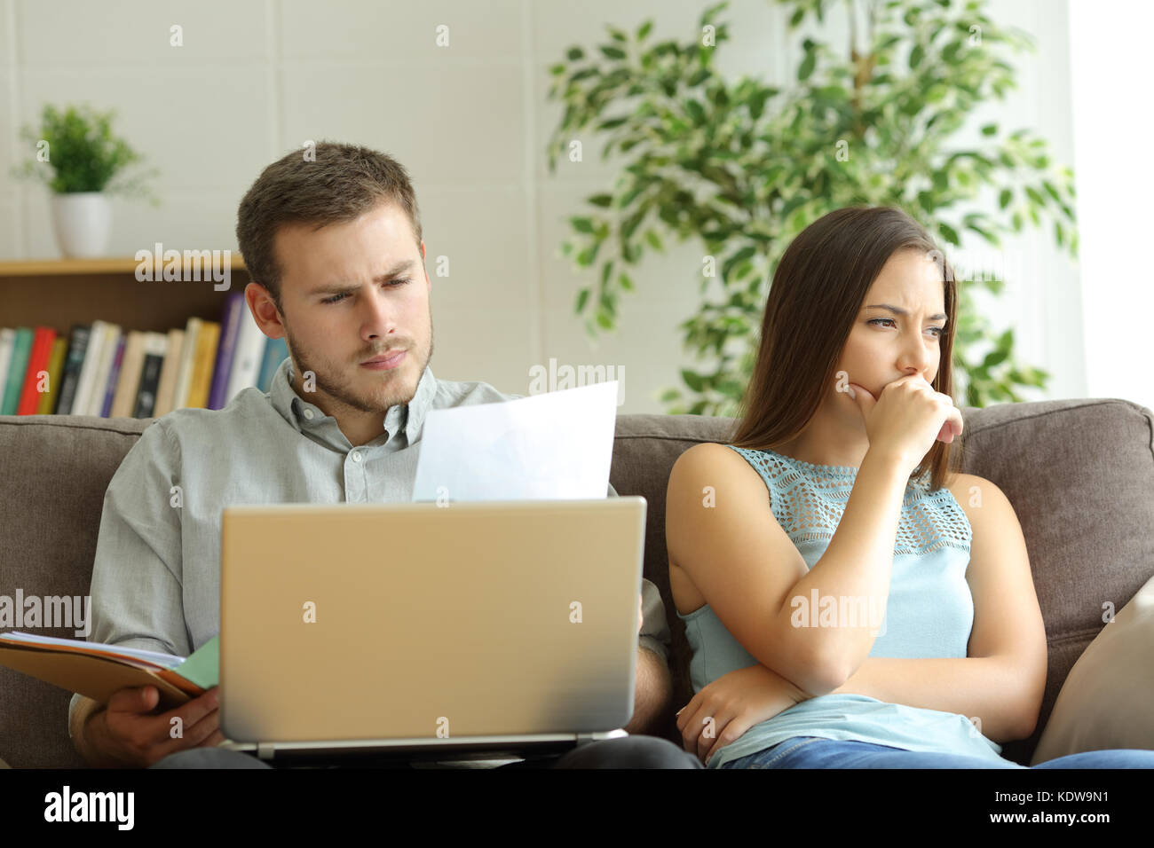 Mann süchtig nach Arbeit und unzufriedenen Frau neben ihm weg schauen sitzen auf einer Couch zu Hause Stockfoto