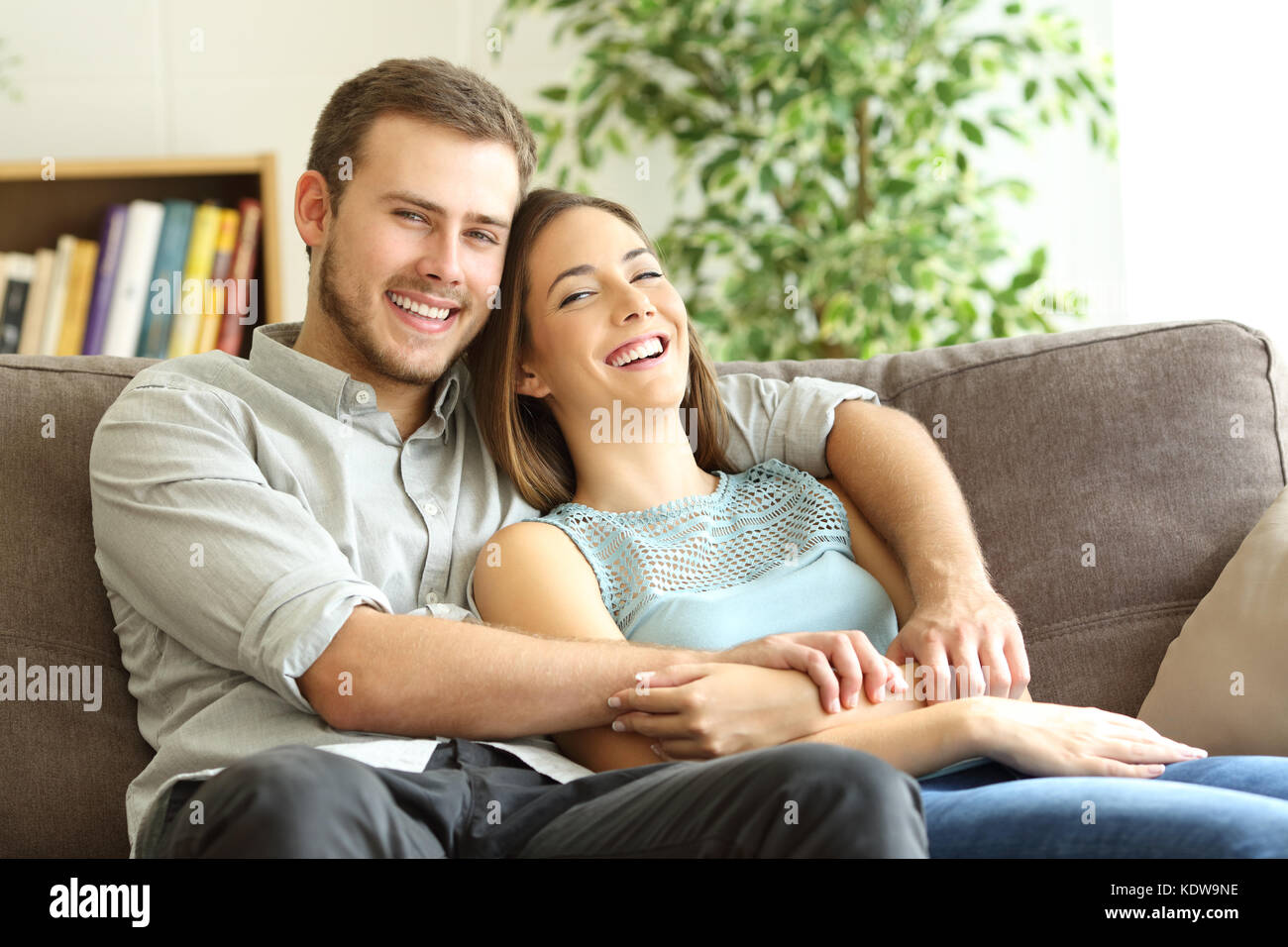 Glückliches Paar umarmen und posiert auf Kamera sitzen auf einer Couch zu Hause Stockfoto
