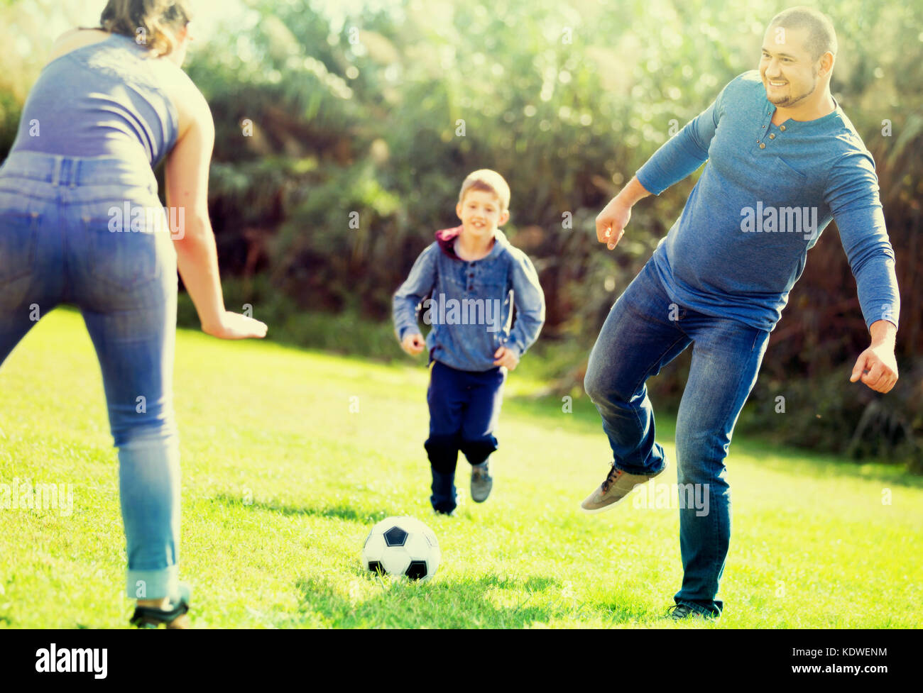 Portrait von aktiven Fröhliche positive Familie Fußball spielen mit Sohn im Freien Stockfoto
