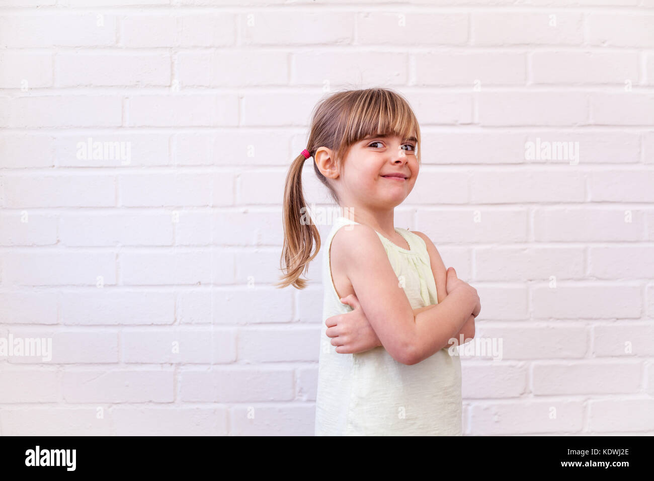 Attraktive kleine blonde Mädchen Profil Brustbild. Cute kid mit Waffen gegen die weiße Wand gefaltet Stockfoto