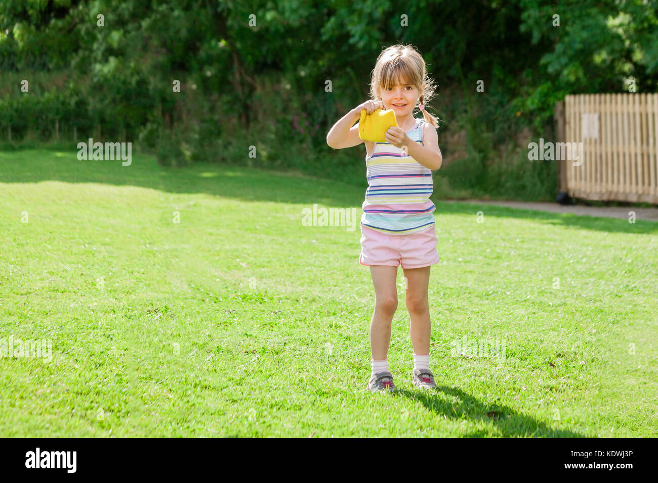 Cute elementare Alter kleines Mädchen am Tag des Sports Holding eine gelbe Bohne Beutel. gerne Spaß zurück in die Schule. Stockfoto