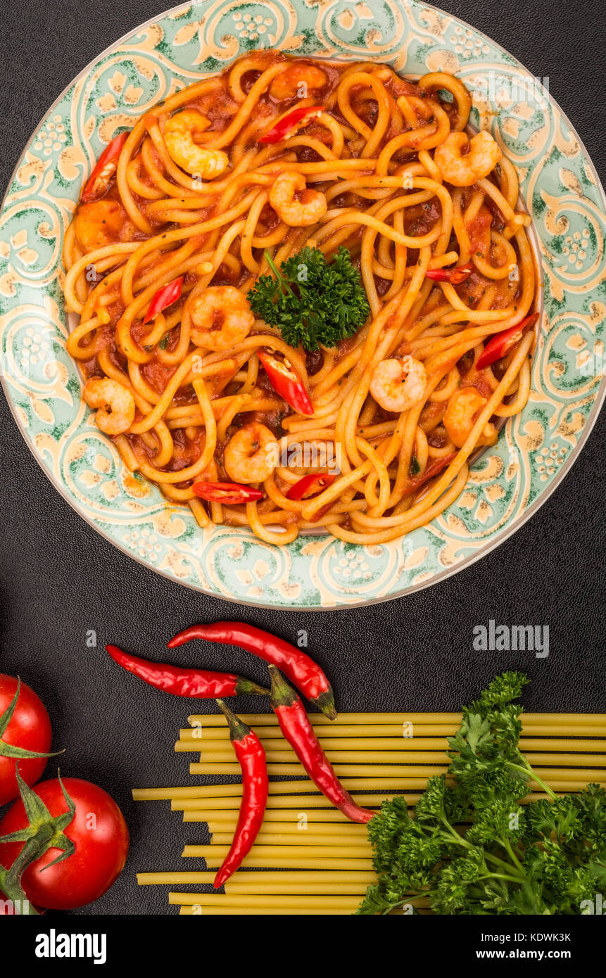 Im italienischen Stil würzige Garnelen oder Shrimps Spaghetti in einem Chili Tomatensauce auf schwarzem Hintergrund Stockfoto