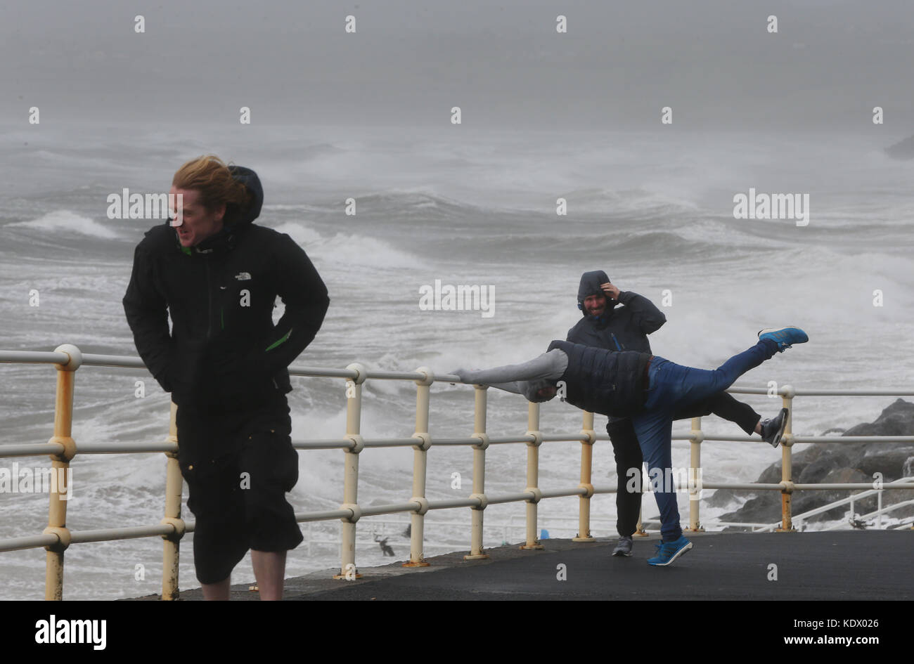 In Lahinch in der Grafschaft Clare an der Westküste Irlands kämpfen die Menschen gegen die Wellen und den starken Wind, als Hurrikan Ophelia Großbritannien und Irland mit Böen von bis zu 80 km/h trifft. Stockfoto