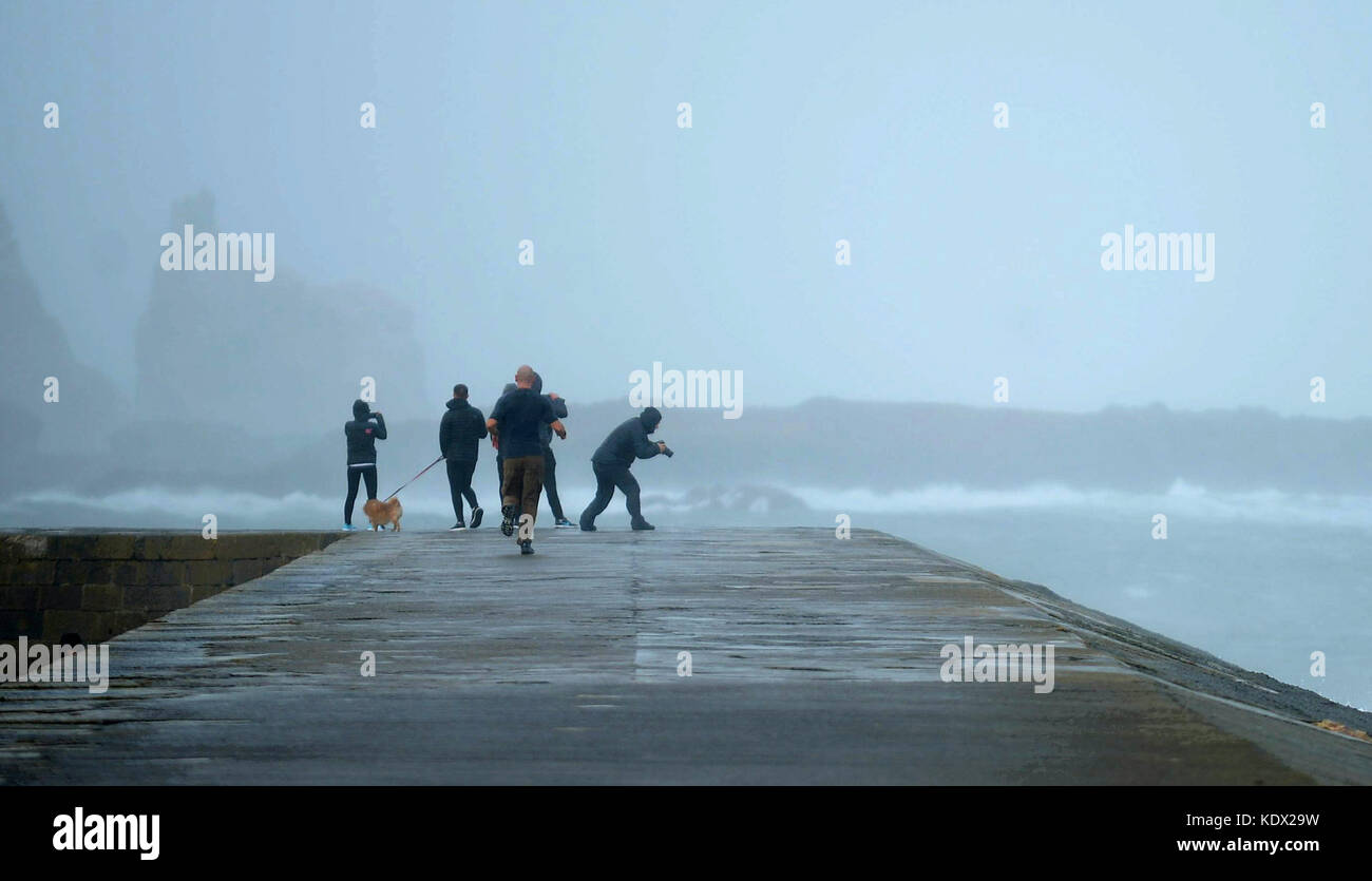Menschen an der Pier-Wand während des Sturms Ophelia am East Pier in Howth, Dublin, Irland, als Hurkan Ophelia Großbritannien und Irland mit Böen von bis zu 80 km/h bekämpft. Stockfoto