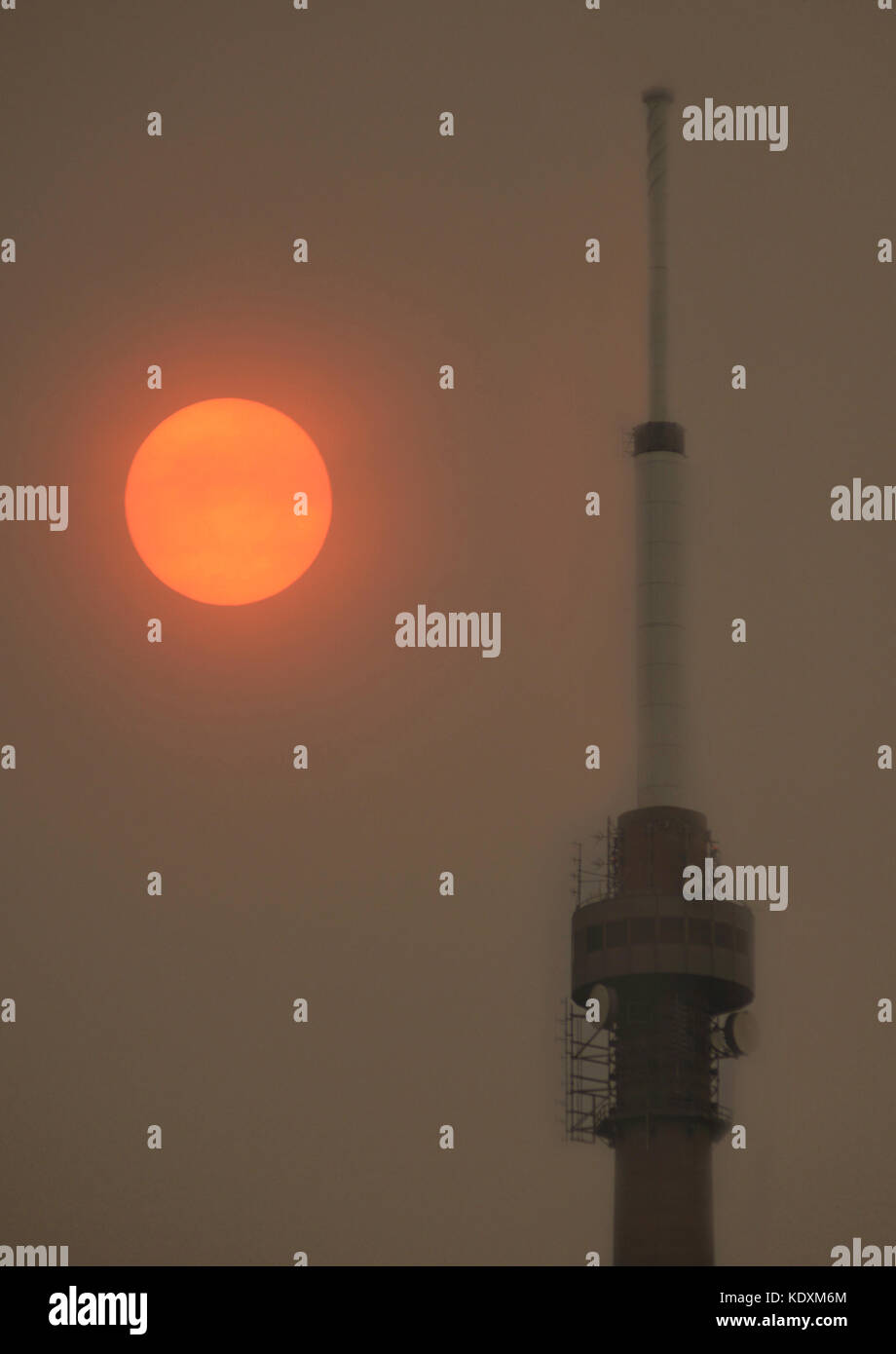 Emley Moor Mast mit Sand in der Luft über die uk durchgebrannt durch Sturm Ophelia, die eine helle rote Sonne über Großbritannien, kirklees, West Yorkshire erscheinen, Stockfoto