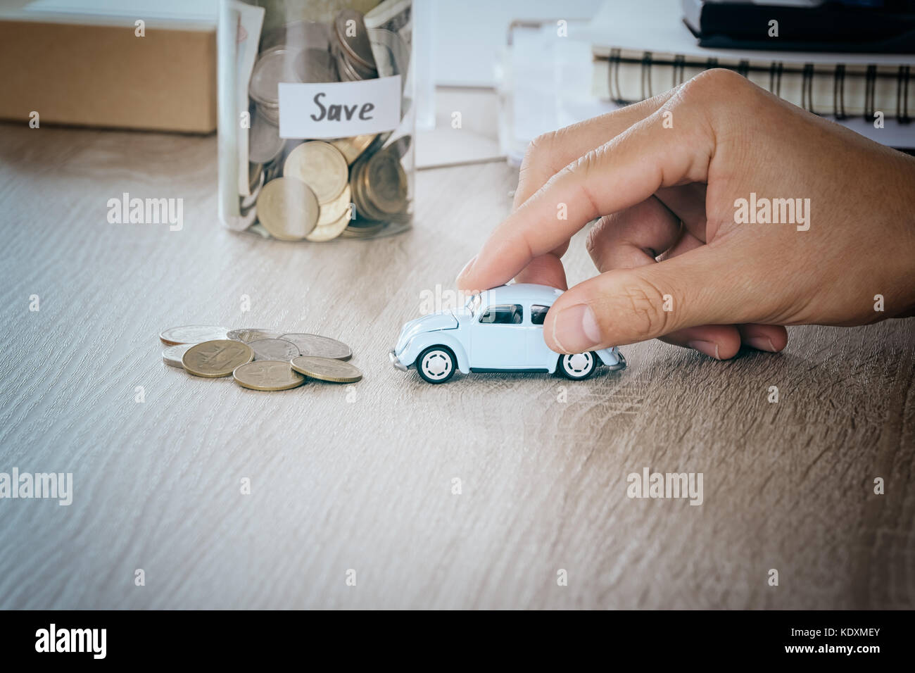 Auto in Männer Hand auf Schreibtisch mit blured Geld Münze in den jar-bank speichern Konzept für Wartung Kosten und Steuern Auto, warmen Ton Filter Stockfoto