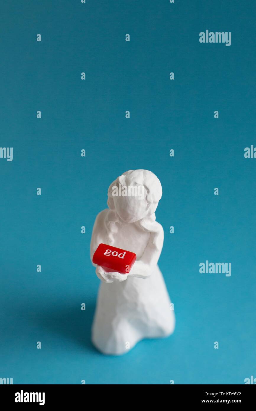 Eine weiße Figur von einer Frau mit einem roten Block, die lautet: "Gott". Stockfoto
