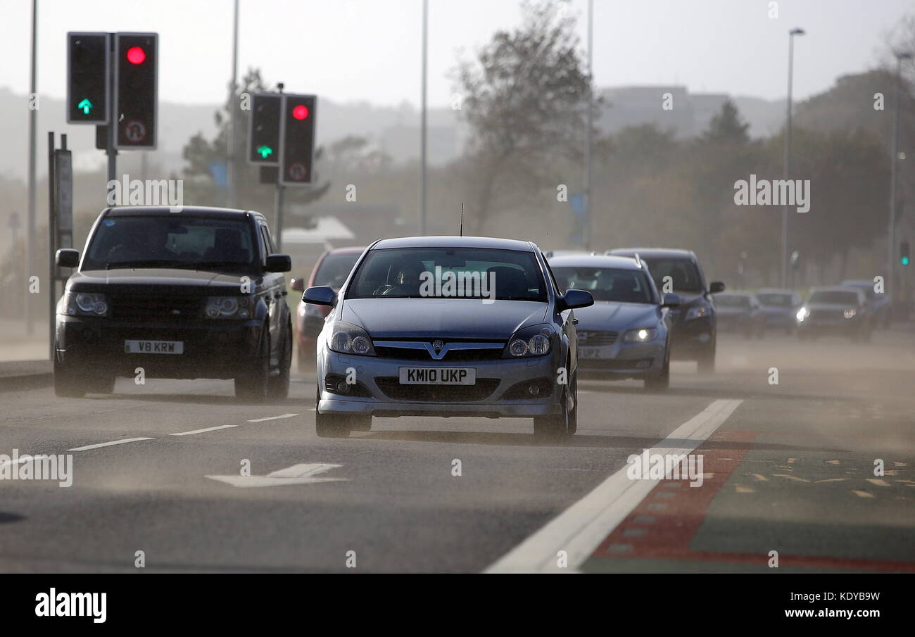 Im Bild: Autos fahren auf Oystermouth Weg gesprengt durch Sand vom Strand in Swansea, Großbritannien geblasen. Montag, 16 Oktober 2017 Re: Reste des Hurrikans Stockfoto