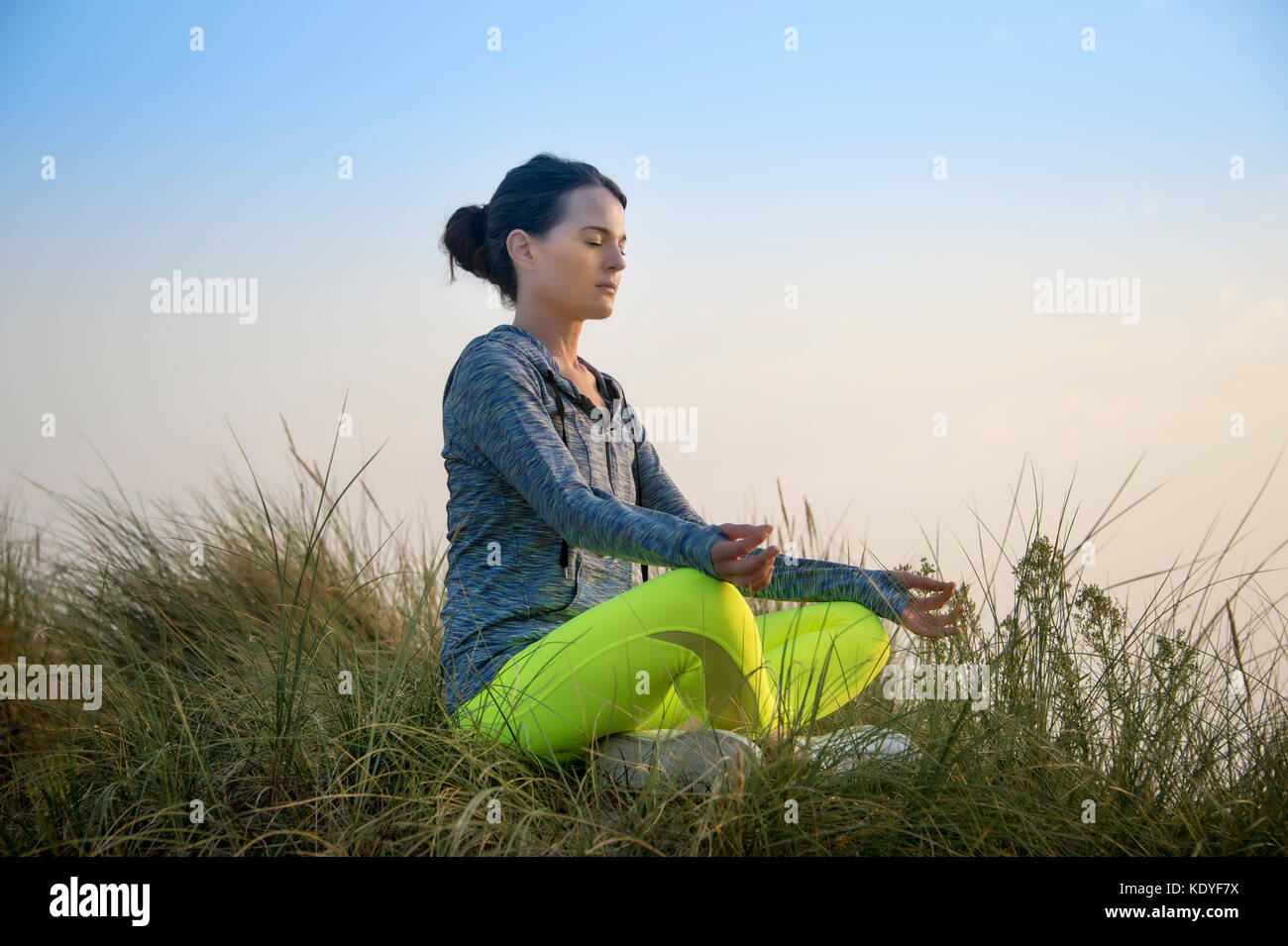 Frau Meditieren in den Sanddünen bei Sonnenaufgang/Sonnenuntergang, Yoga Stockfoto