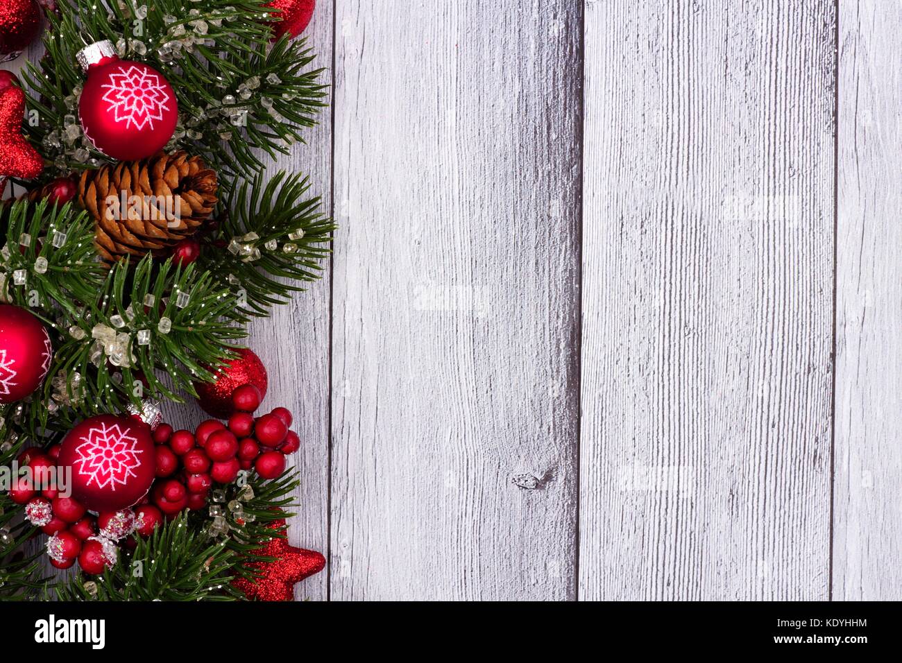 Red christmas Ornamente und Niederlassungen Seite Grenze auf einem urigen weiß Holz Hintergrund Stockfoto