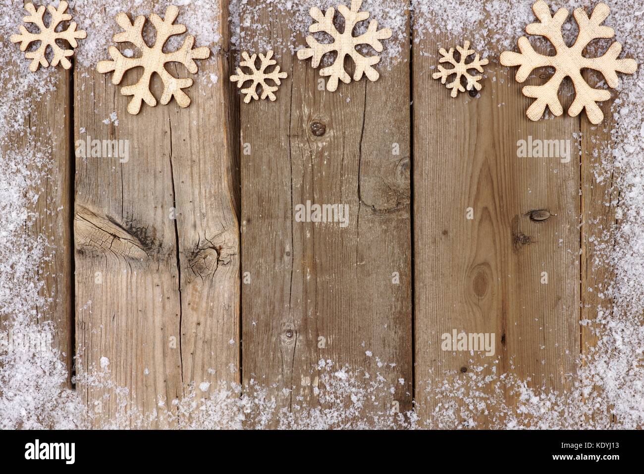 Weihnachten Holz- Schneeflocke oberer Rand mit Schnee Rahmen auf eine rustikale Holz Hintergrund Stockfoto