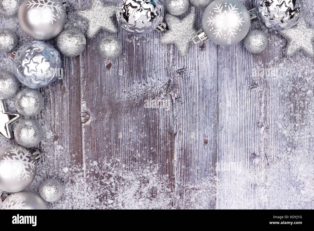Silber Weihnachtsverzierung oberen Ecke Grenze mit Schnee Rahmen auf eine rustikale Holz Hintergrund Stockfoto