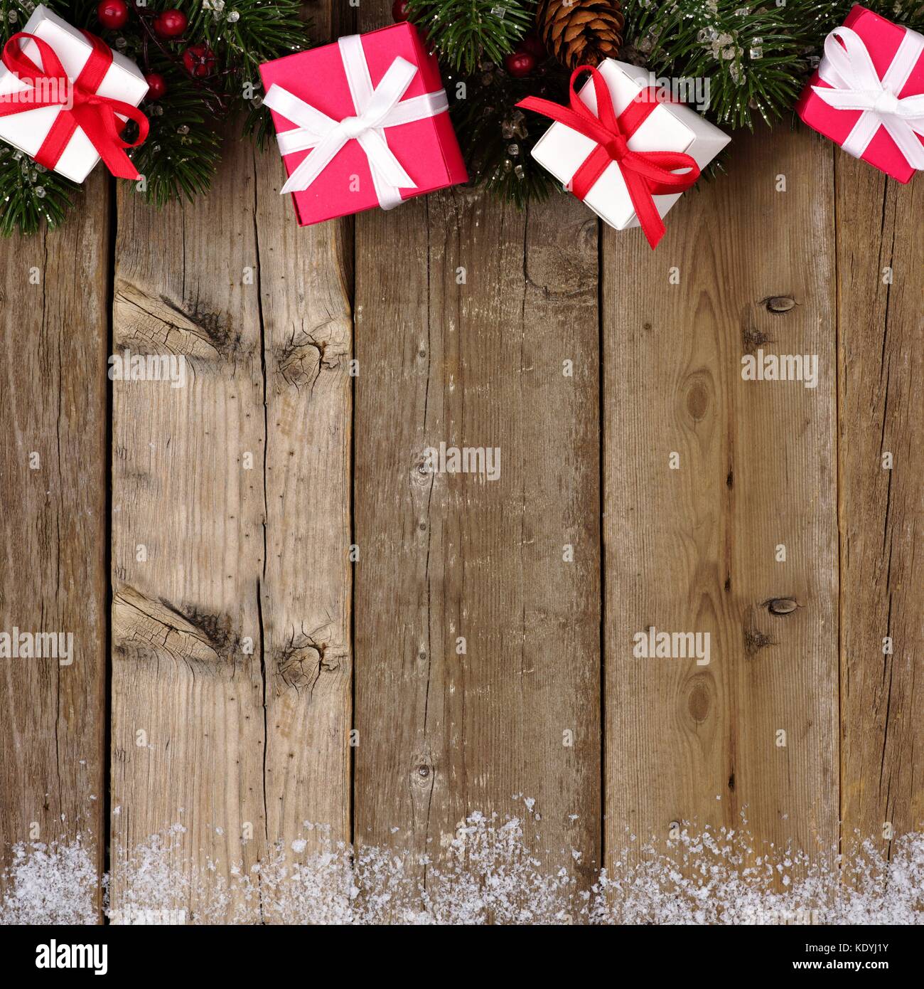 Rote und weiße Weihnachten Geschenk Grenze mit Niederlassungen und Schnee auf einem rustikalen, mit Holz Hintergrund Stockfoto