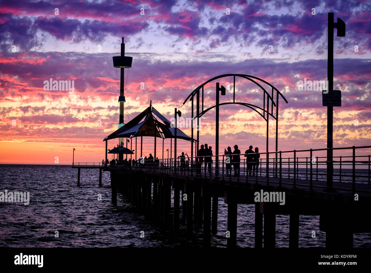 Die Menschen genießen einen wunderschönen Sonnenuntergang am Meer auf der Adelaide von Brighton Pier an einem lauen Sommerabend. Stockfoto