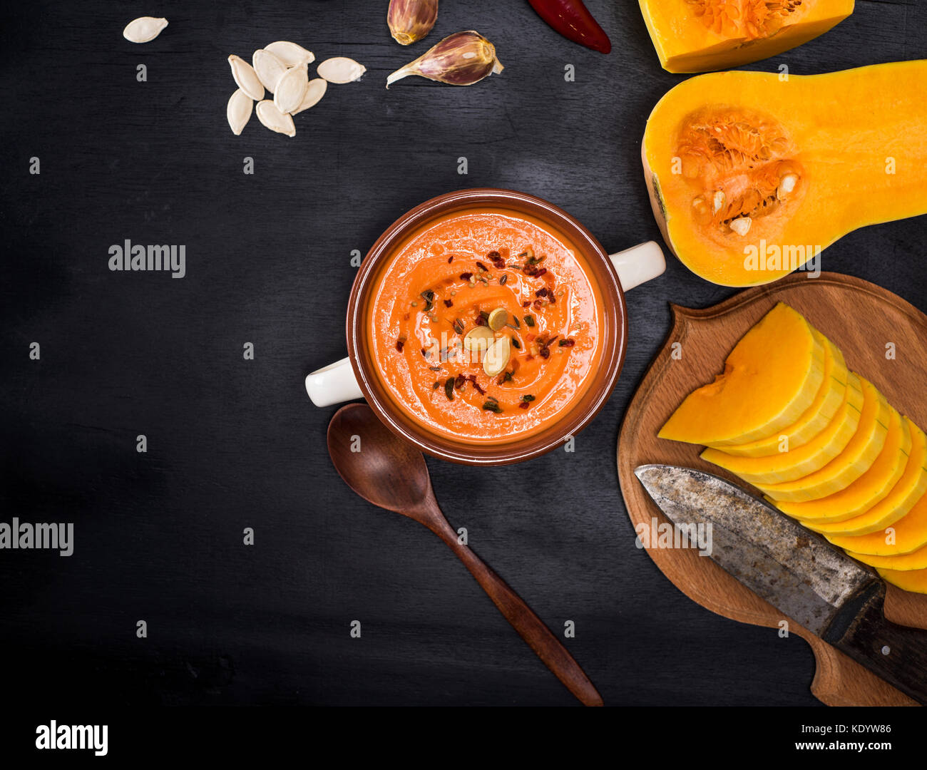 Sahne frische Kürbis Suppe in einer Runde Keramik Teller und Zutaten zum Kochen auf einem schwarzen Hintergrund, leeren Raum auf der linken Seite Stockfoto
