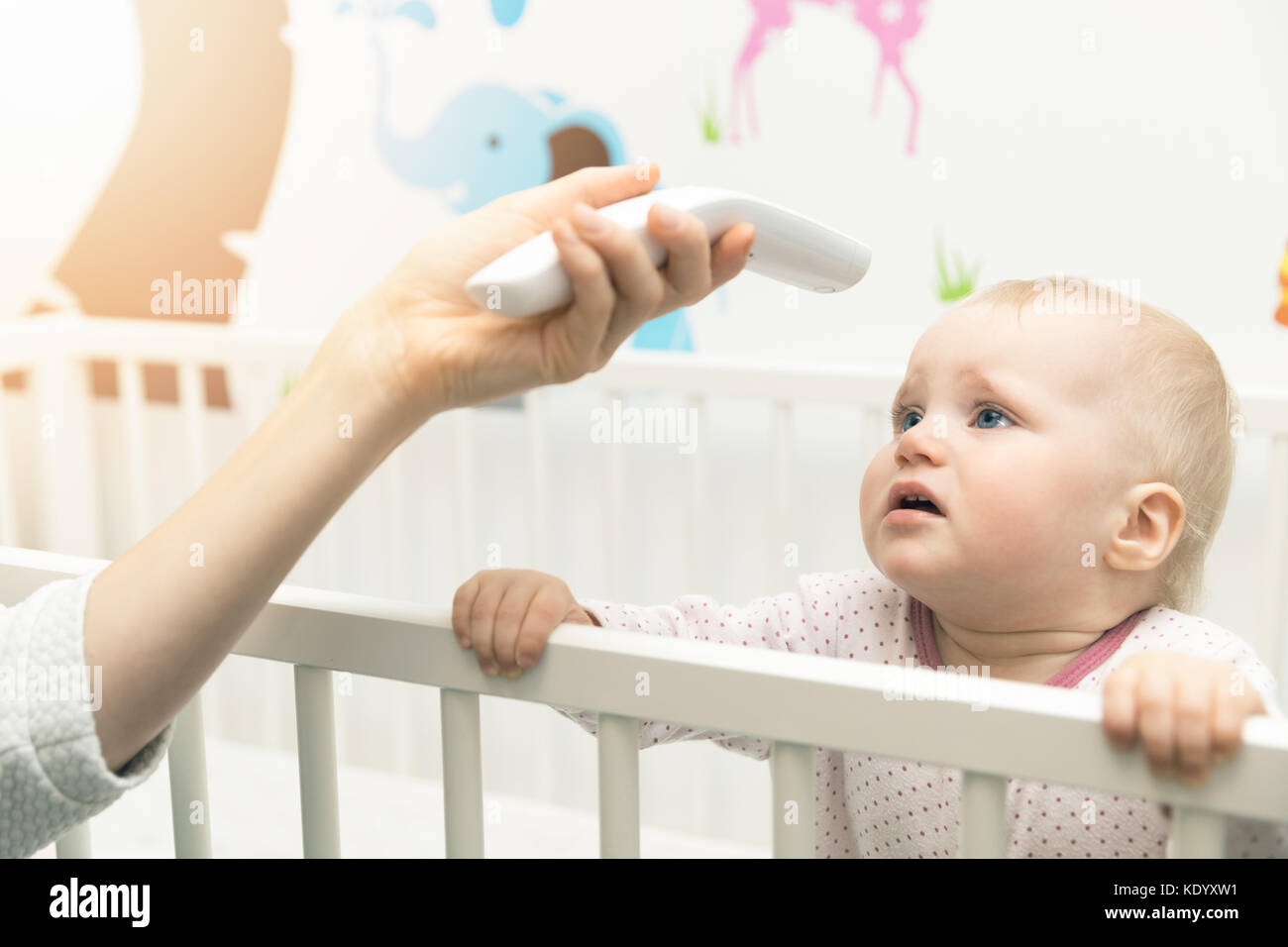 Mutter Überprüfen Sie die Temperatur des Babys mit nicht Kontaktthermometer Stockfoto