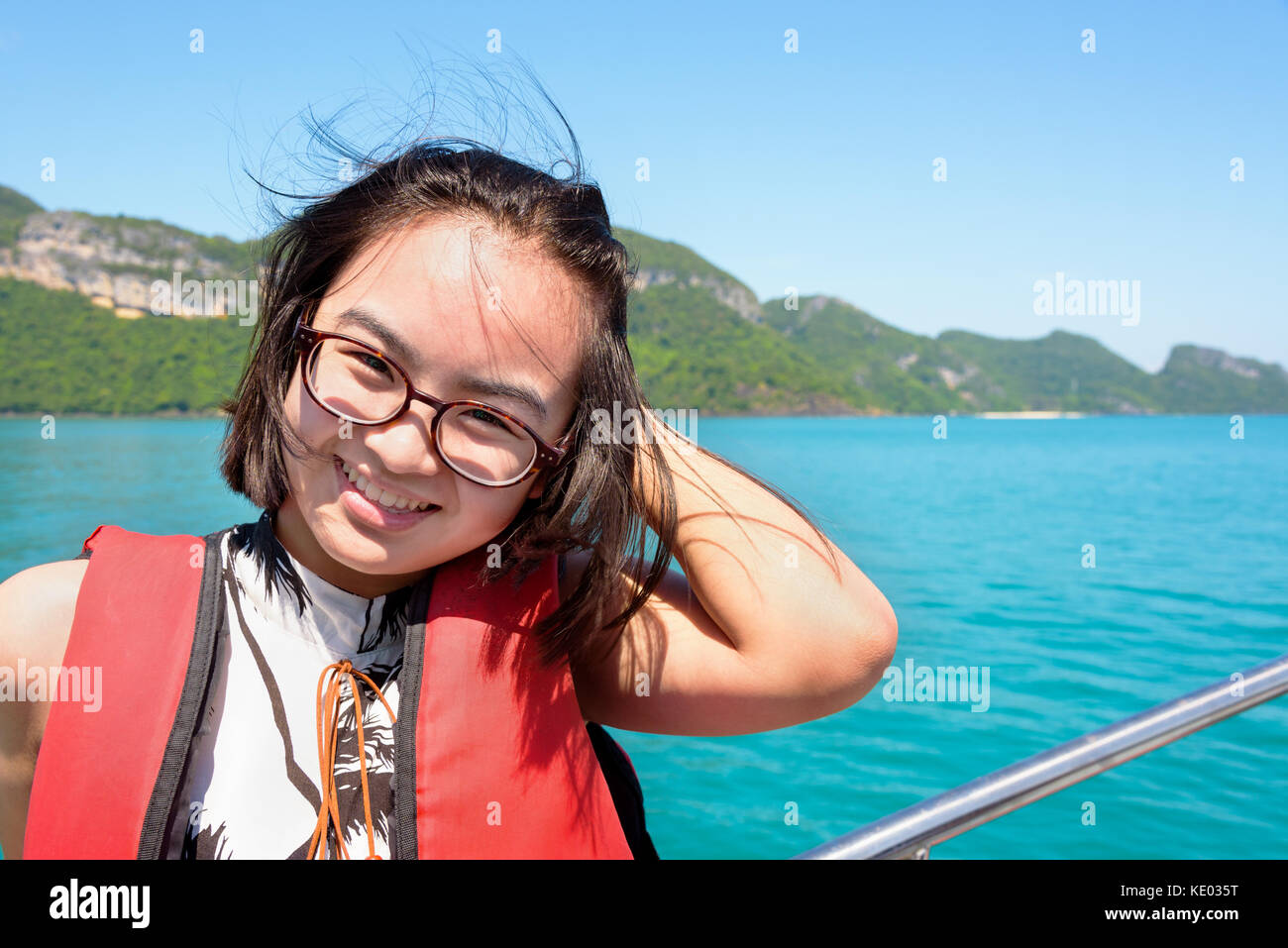 Nette junge Frau mit Brille glücklich lächelnd auf dem Boot, während die schöne Natur der blauen Himmel und Meer Kreuzfahrt im Sommer an Mu Ko Ang Thong Stockfoto
