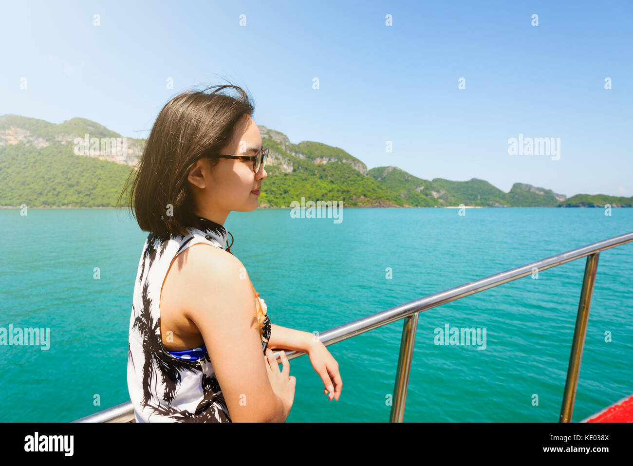Nette junge Frau mit Brille glücklich lächelnd auf dem Boot während der Fahrt die Natur der Insel und unter Sonneneinstrahlung im Sommer an Mu Ko Ang Thong Stockfoto