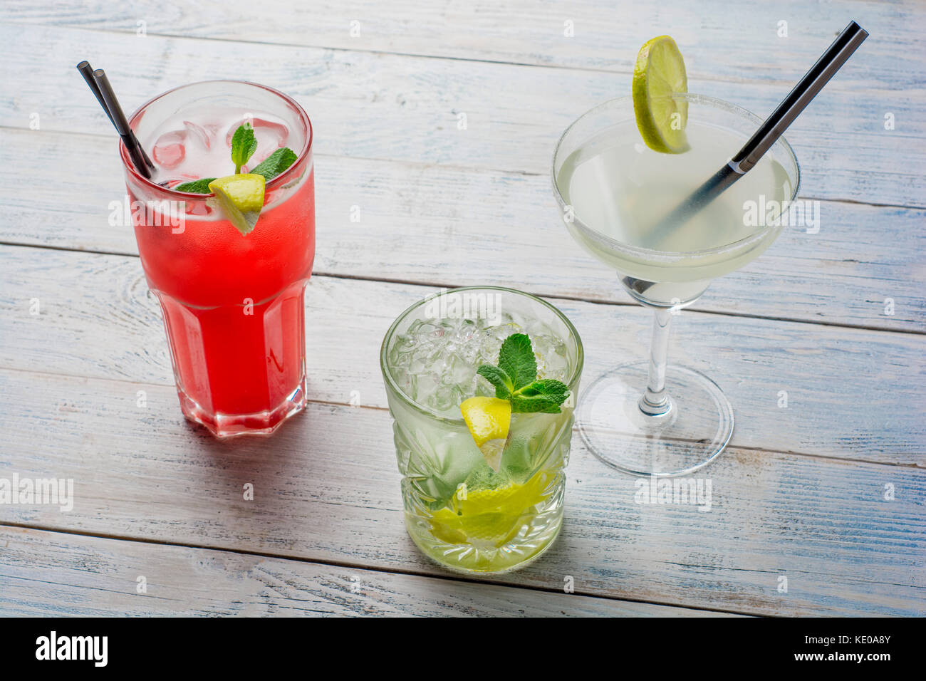 Farbenfrohe Cocktails. Mojito, rote Cocktail mit Eis und Kalk, Margarita auf hölzernen Tisch. Stockfoto