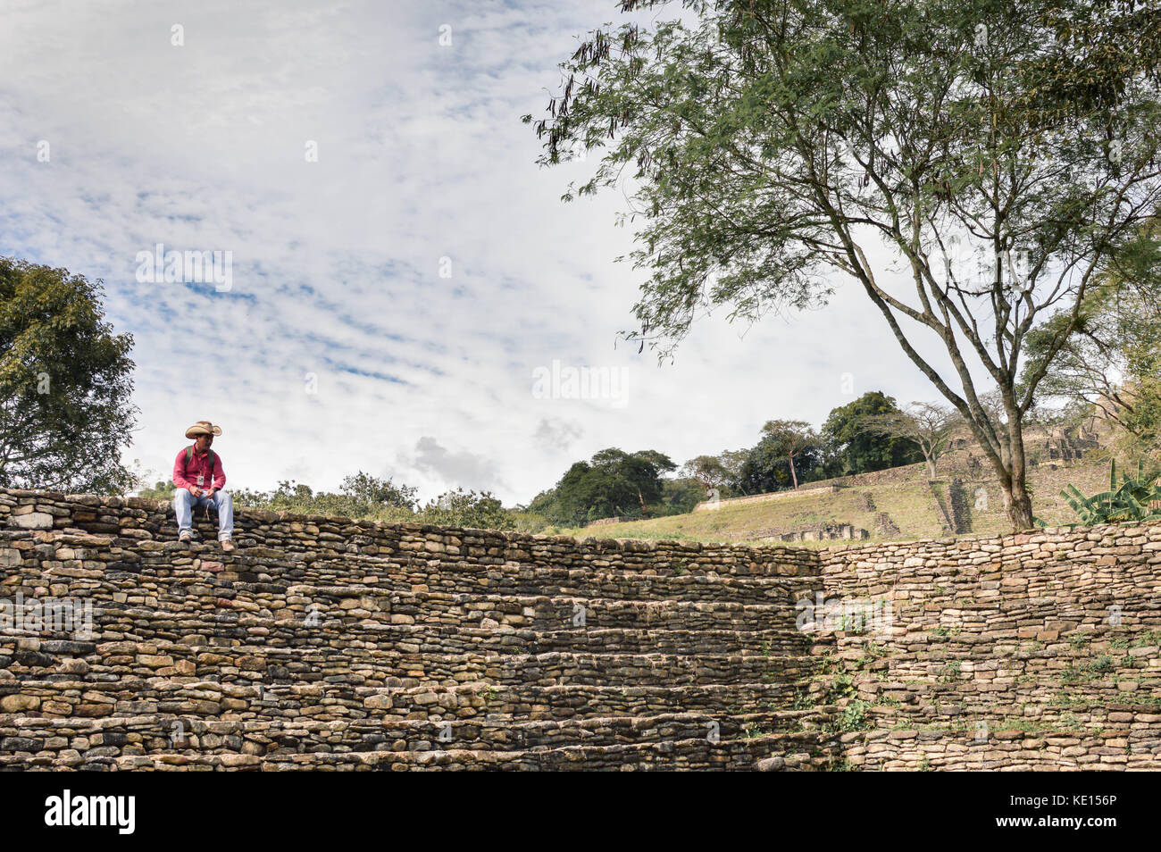 Ocosingo, Mexiko - 9. Januar 2015: Ortskundiger Reiseleiter rastet auf den Stufen einer der Pyramiden der archäologischen Stätte Tonina in Chiapas, Mexiko, aus Stockfoto