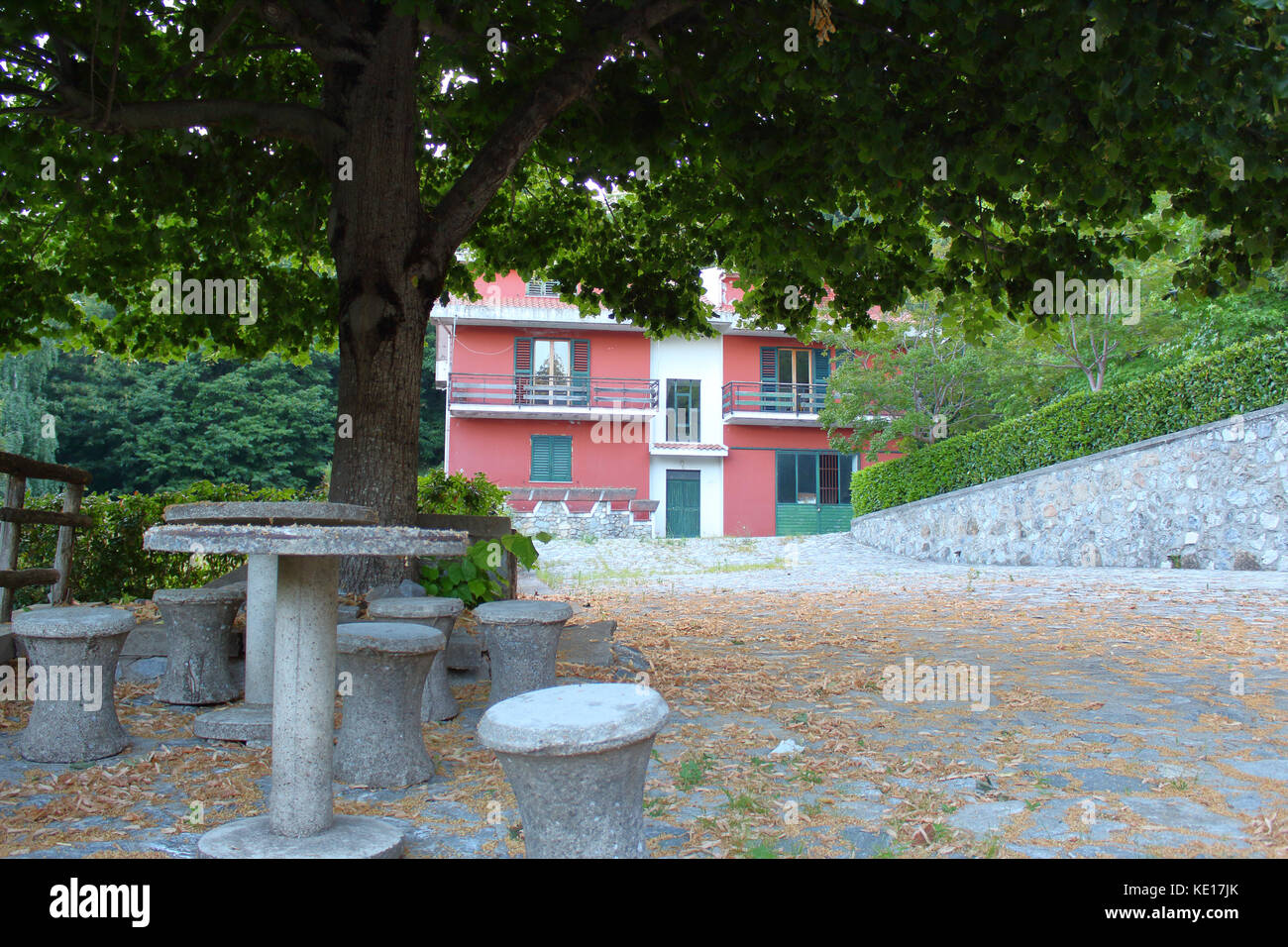 Rosa Gebäude im Wald mit einem Stein Picknicktisch im Vordergrund. Kalabrien, Italien. Stockfoto