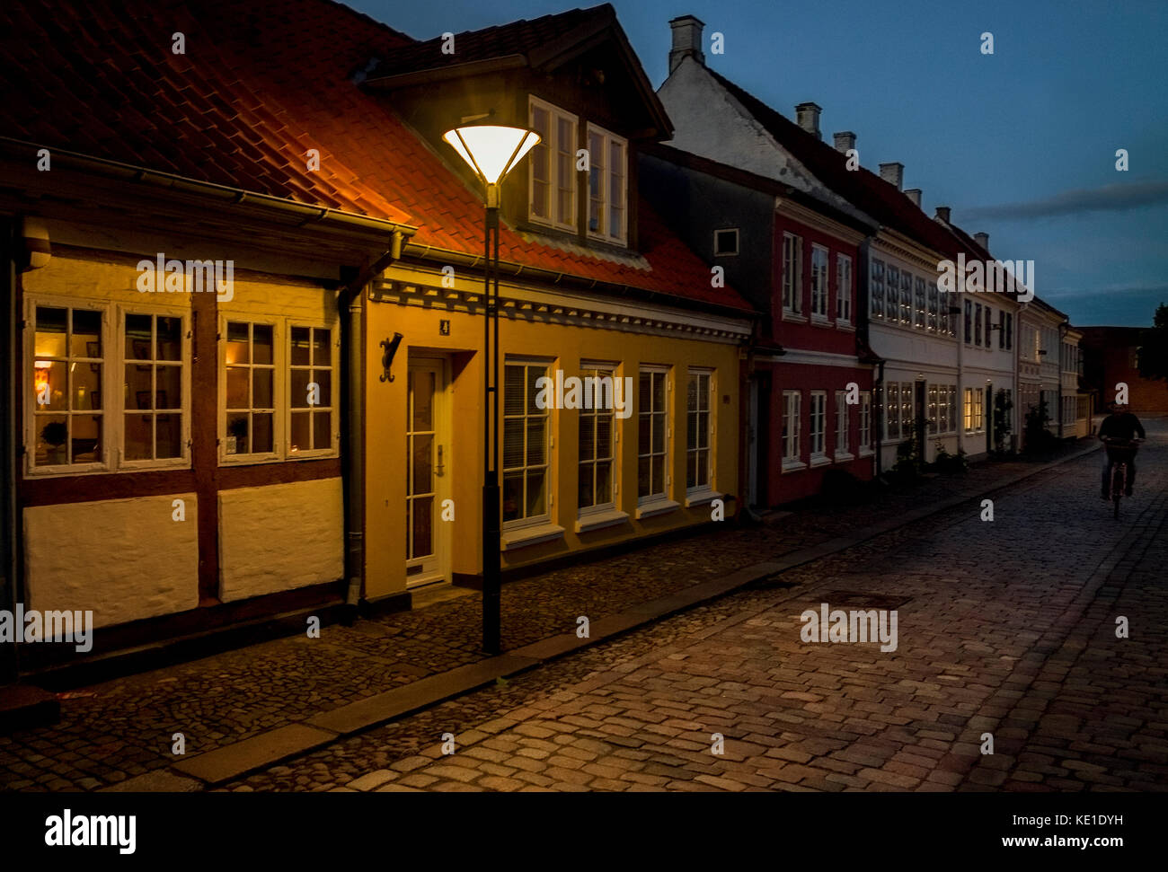 Nachtansicht der traditionellen gepflasterten Straße alte Häuser beleuchtet durch einzelne straßenlaterne Odense Dänemark Stockfoto