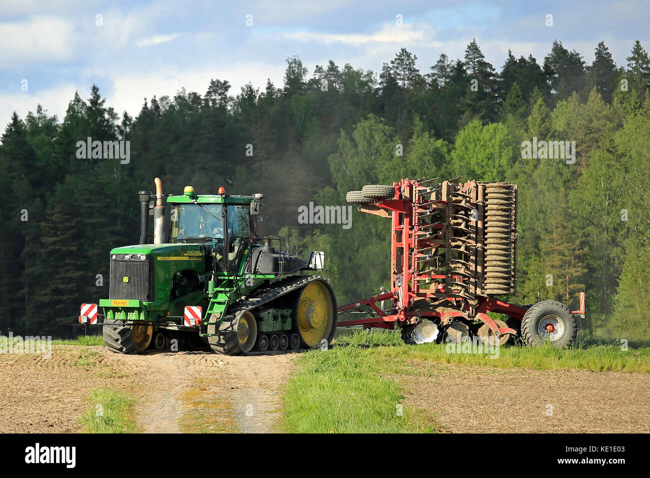 Salo, Finnland - 27. Mai 2016: John Deere 9520t Raupenschlepper und kultivator Verschieben entlang der Piste in ländlichen Frühling Landschaft auf dem Weg Stockfoto