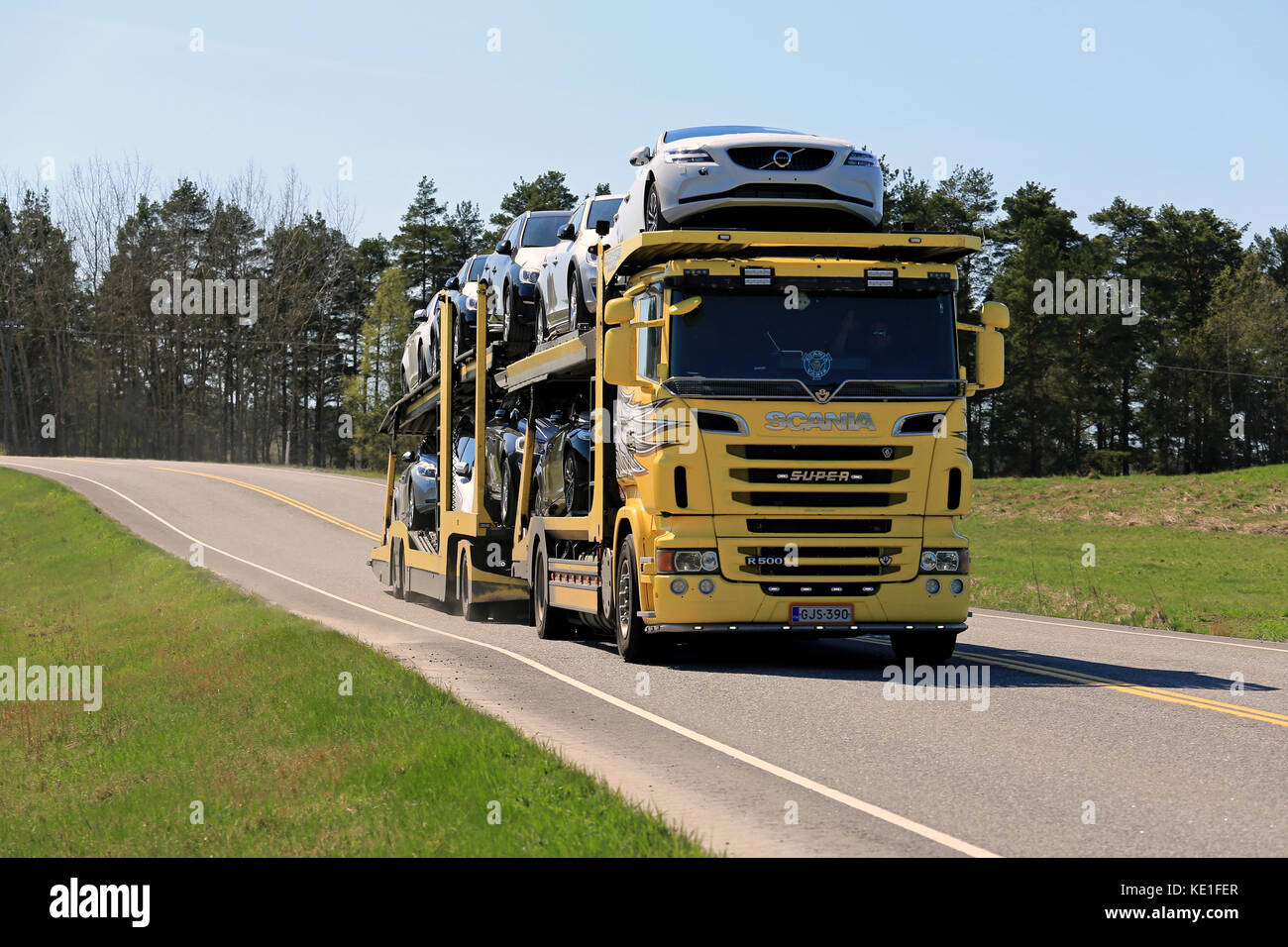 Salo, Finnland - 8. Mai 2016: gelb Scania R500 Lkw schleppt eine Last von neuen Autos entlang hiighway im Süden Finnlands an einem sonnigen Tag des Frühlings. Stockfoto