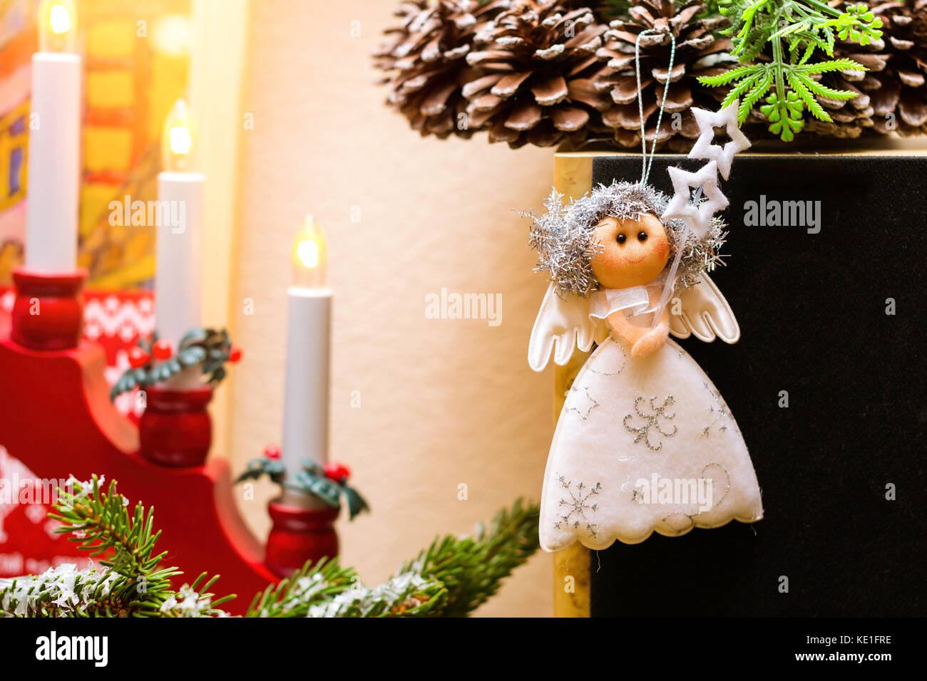 Weihnachten Engel rag doll hängen an Weihnachten Kranz mit Tannenzapfen. Inmitten einer festlichen Kerzenständer mit Kerzen. Feier des neuen Jahres und Weihnachten Stockfoto