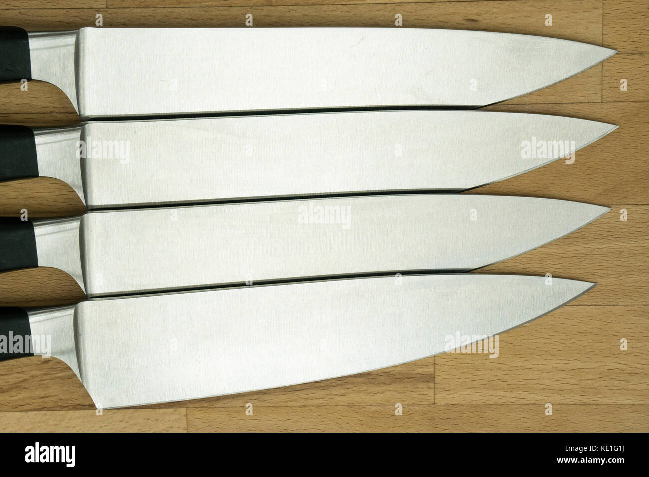Vier identische Küche Messer auf einer hölzernen Arbeit top Stockfoto