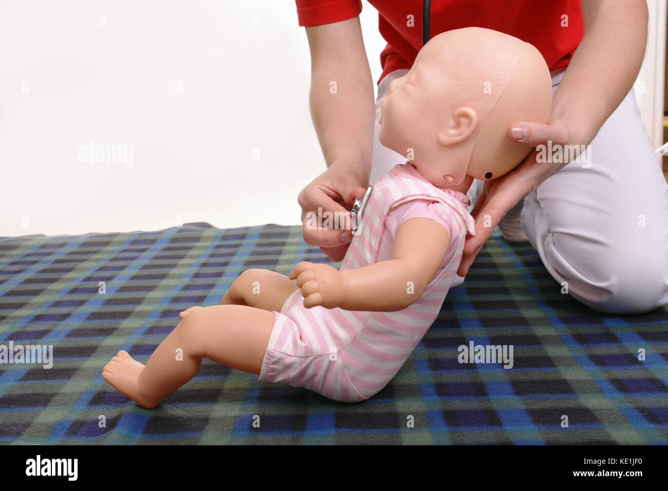 Erste Hilfe Ausbilder mit Kleinkind Dummy, um zu zeigen, wie sie ihr Baby mit Stethoskop zu prüfen Stockfoto