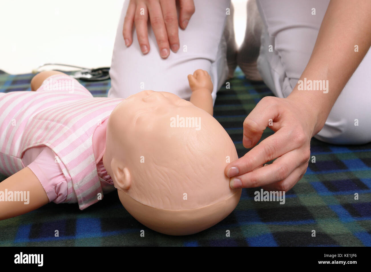 Kleinkinder Erste Hilfe - Erste Hilfe Ausbilder zeigen, wie Impuls auf Kleinkinder dummy anterior Fontanelle zu prüfen. Stockfoto