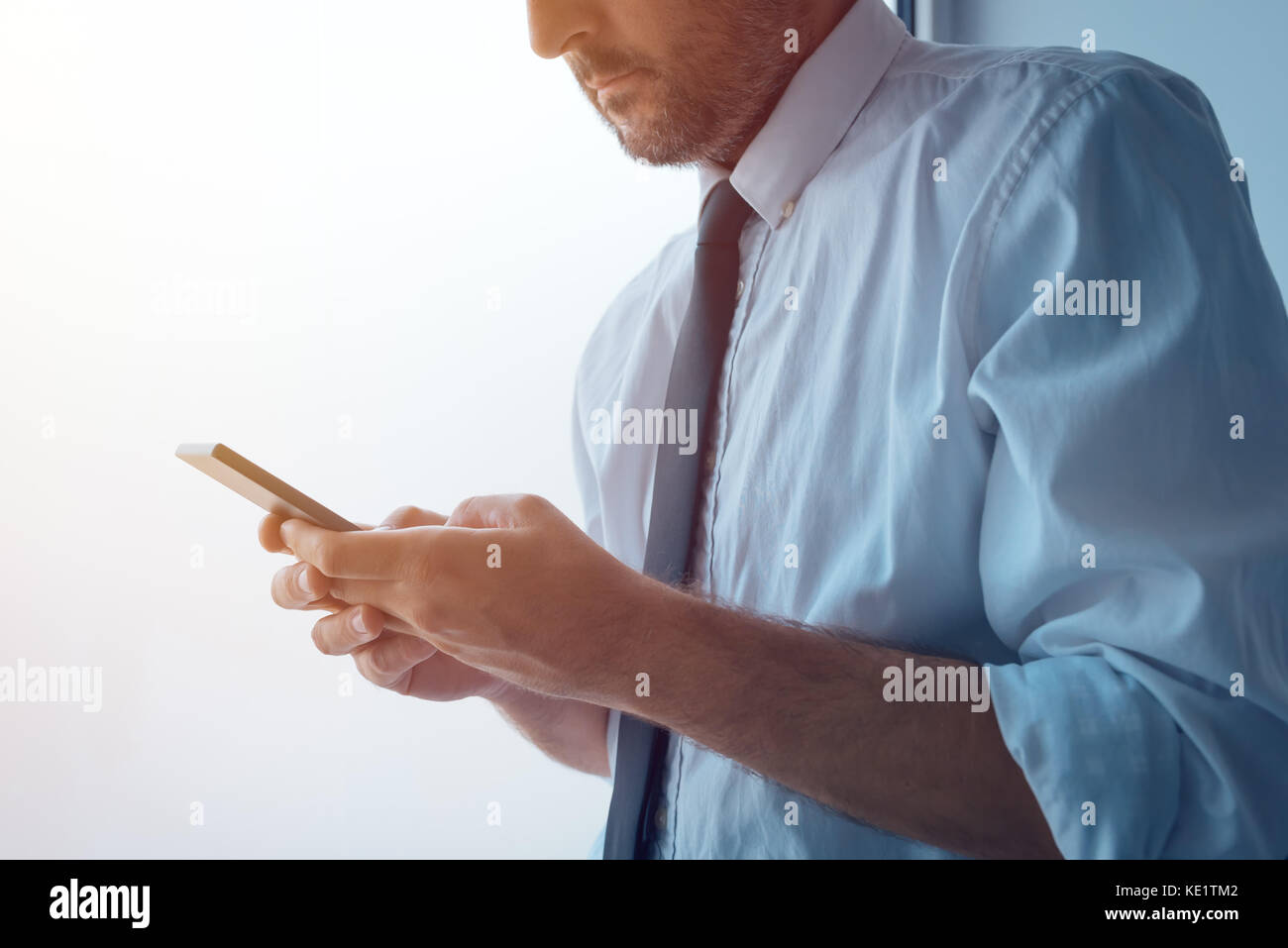 Geschäftsmann neben Büro und texting. Erwachsene kaukasischen business Person im weißen Hemd mit versteckt aufgerollten Ärmeln mit Mobile Phon Stockfoto