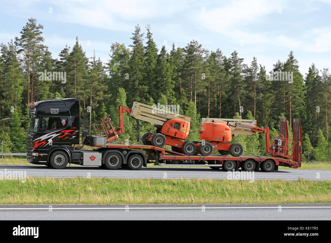 Paimio, Finnland - Juni 3, 2016: schwarz SCANIA LKW-Transporte zwei Hubarbeitsbühnen auf lowboy Trailer entlang der Autobahn im Süden Finnlands. Stockfoto