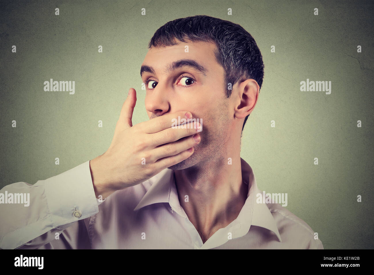 Porträt einer Angst erwachsener Mann mit der Hand über den Mund isoliert auf grauen Hintergrund Stockfoto