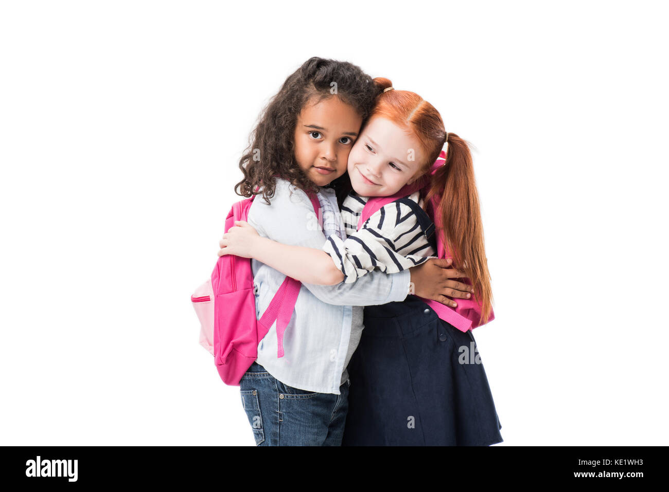 Adorable multiethnischen Schülerinnen mit Rucksäcken umarmen isoliert auf weißem Stockfoto