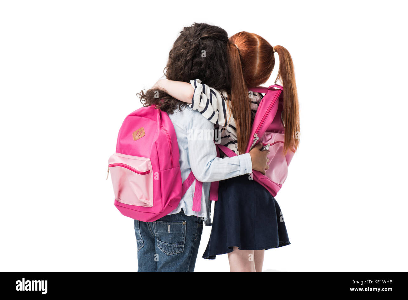 Rückansicht des niedlichen multiethnischen Schülerinnen mit Rucksäcken gemeinsam isoliert auf weißem Stockfoto