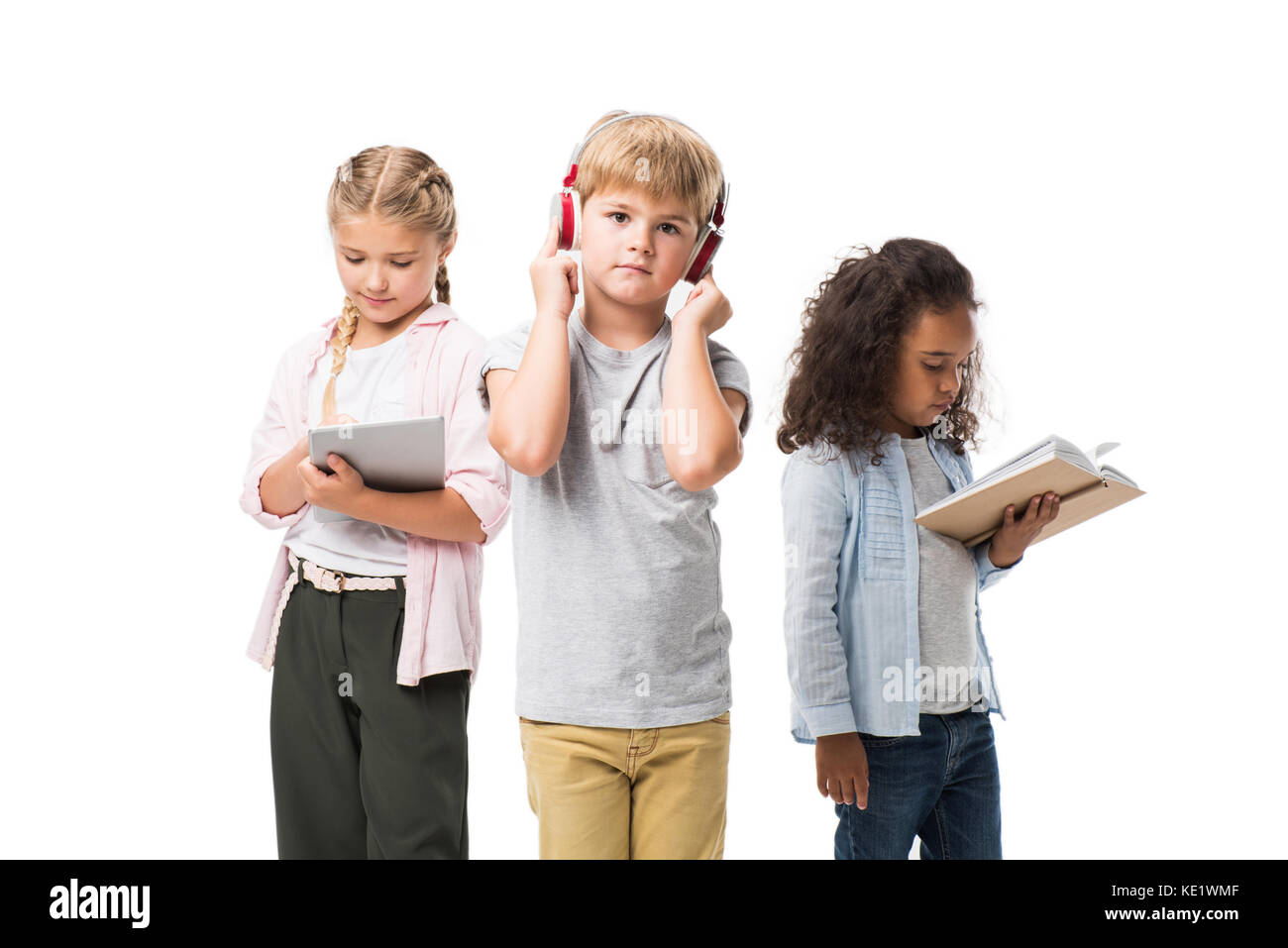Adorable multiethnischen Kinder Musik hören über Kopfhörer, mit digitalen Tablet und lesen Buch isoliert auf weißem Stockfoto
