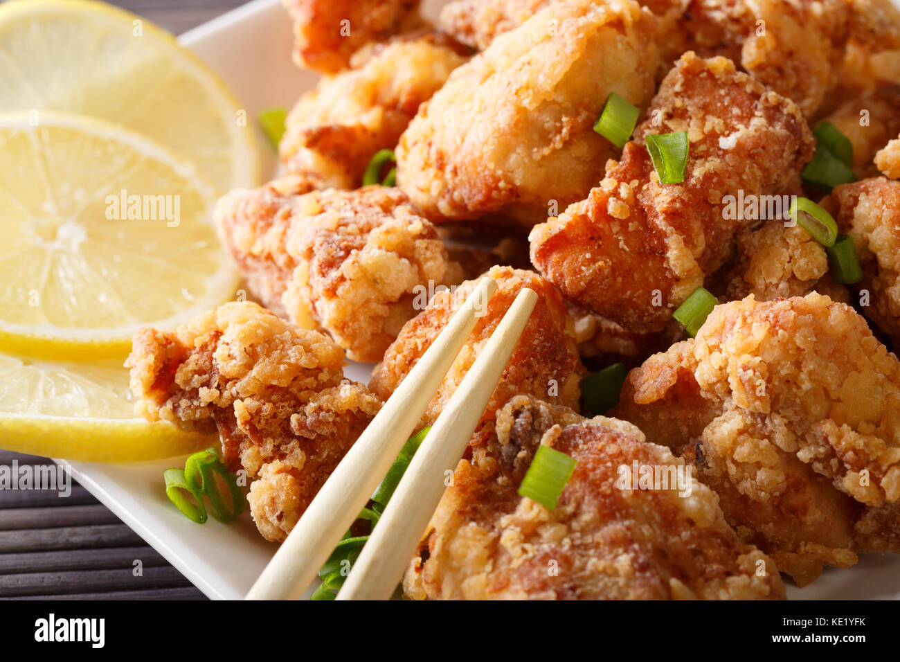 Japanisches Essen: Gebratenes Huhn mit Zitrone und karaage grüne Zwiebel close-up auf einem Teller. Horizontale Stockfoto Japanisches Essen: Gebratenes Huhn mit Zitrone und karaage grüne Zwiebel close-up auf einem Teller. Horizontale Stockfoto