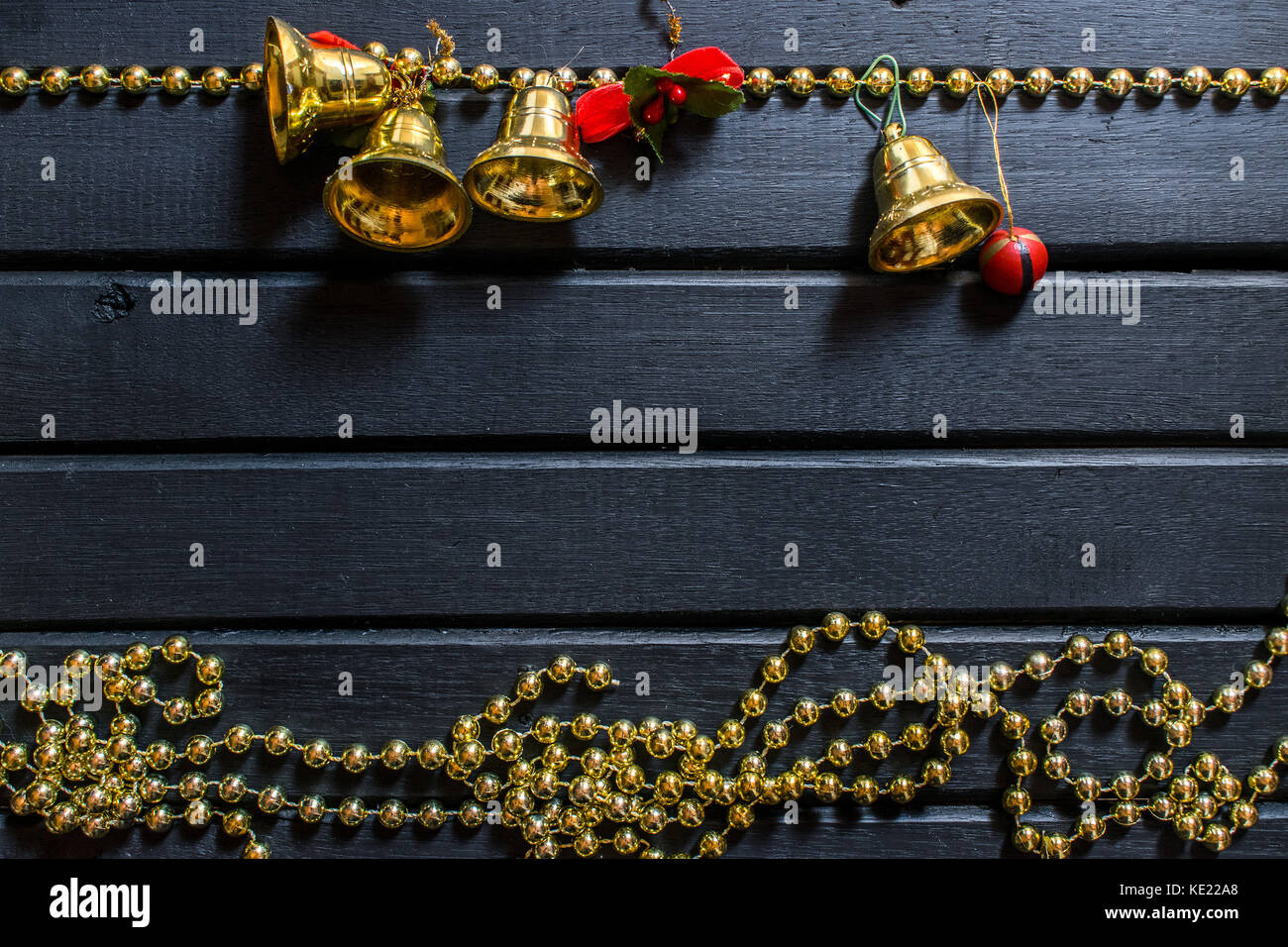 Weihnachtsdekoration Hintergrund, auf einem schwarzen Hintergrund Holz, mit Glocken, Mistel, goldene Ketten, Kugeln und Requisiten und Kette mit Rentier, und Dekor Stockfoto