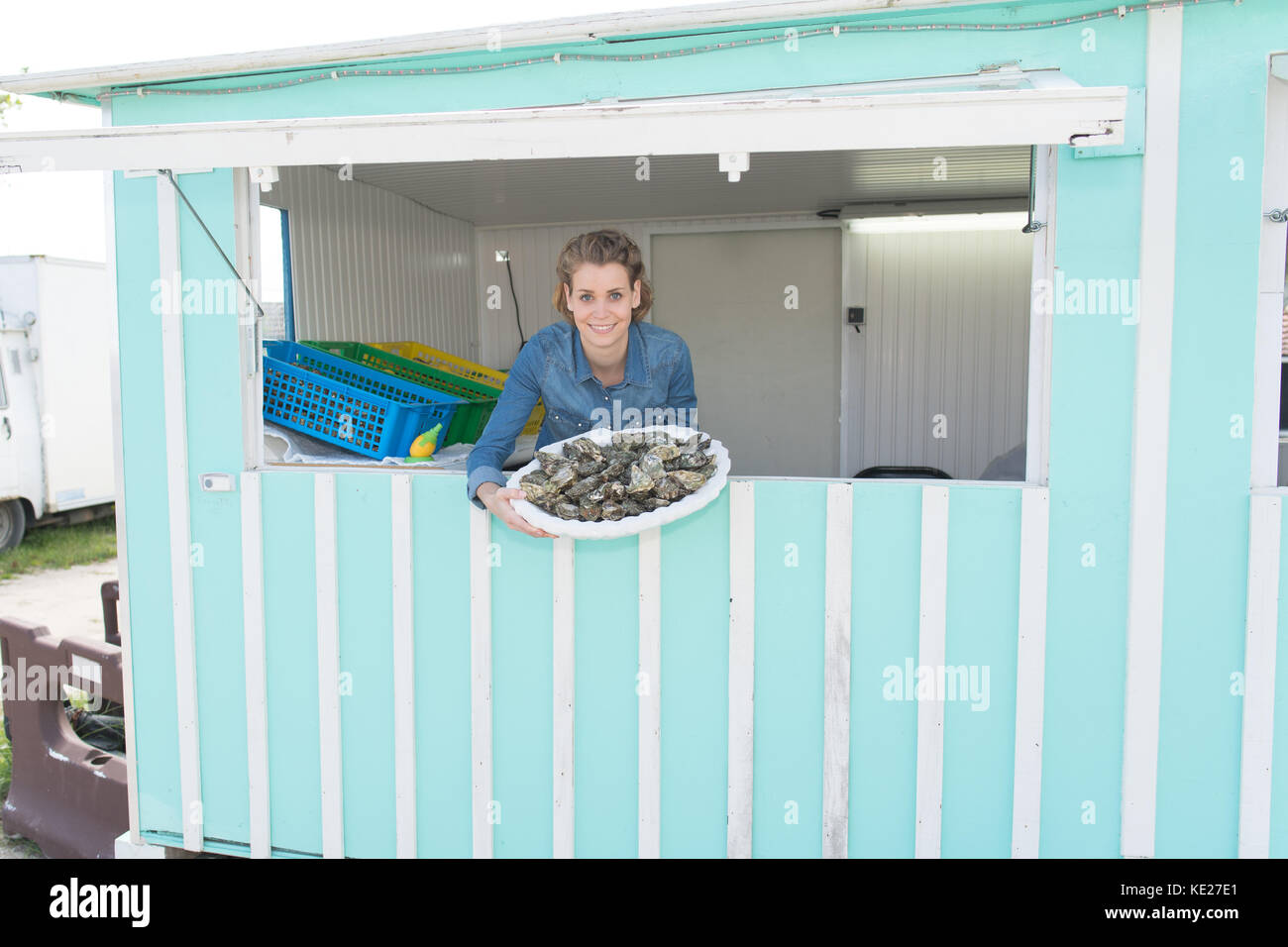 Lächelnd weibliche Verkäufer Austern angezeigt Stockfoto