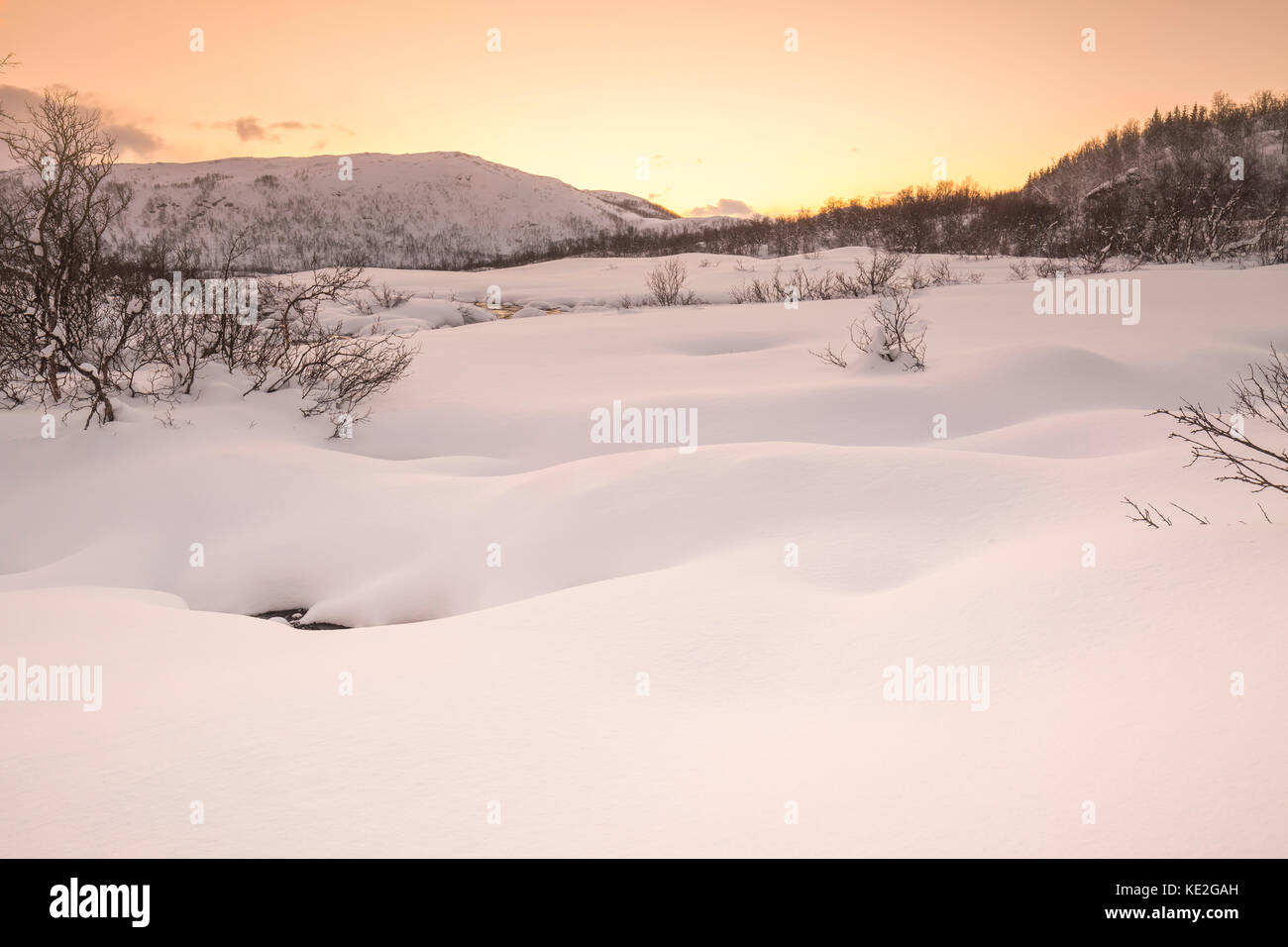 Ein wenig Wasser Fluss mit Felsen auf den Vordergrund mit einem arktischen, verschneite Winterlandschaft im Hintergrund. der Himmel klar ist, vielfältigen und lebendigen Stockfoto