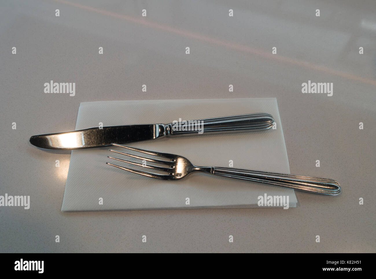 Messer und Gabel und Papier Serviette auf einem weißen Tisch Stockfoto