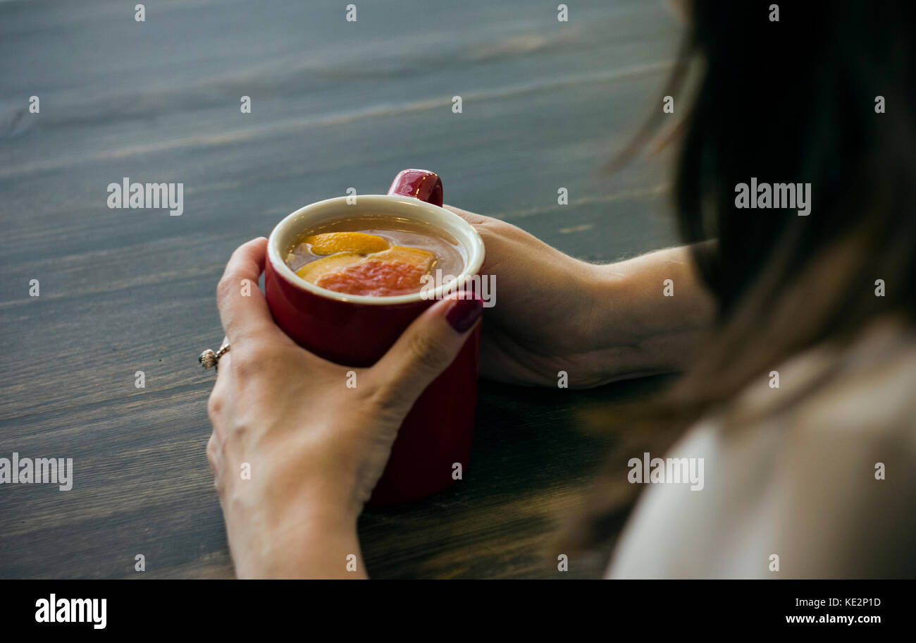 Junge Frau im Cafe Holding in den Händen von heißen Früchte Tee. Einsamkeit, Trauer Stockfoto