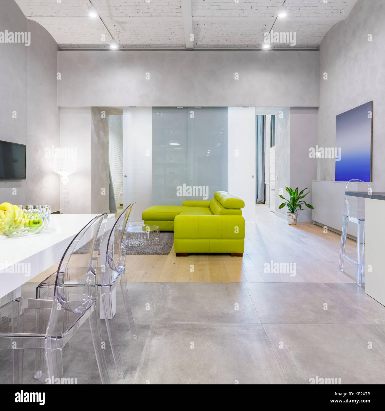 Loft Apartment mit grünen Couch, Tisch, Stühlen und transparenten Glastüren Stockfoto