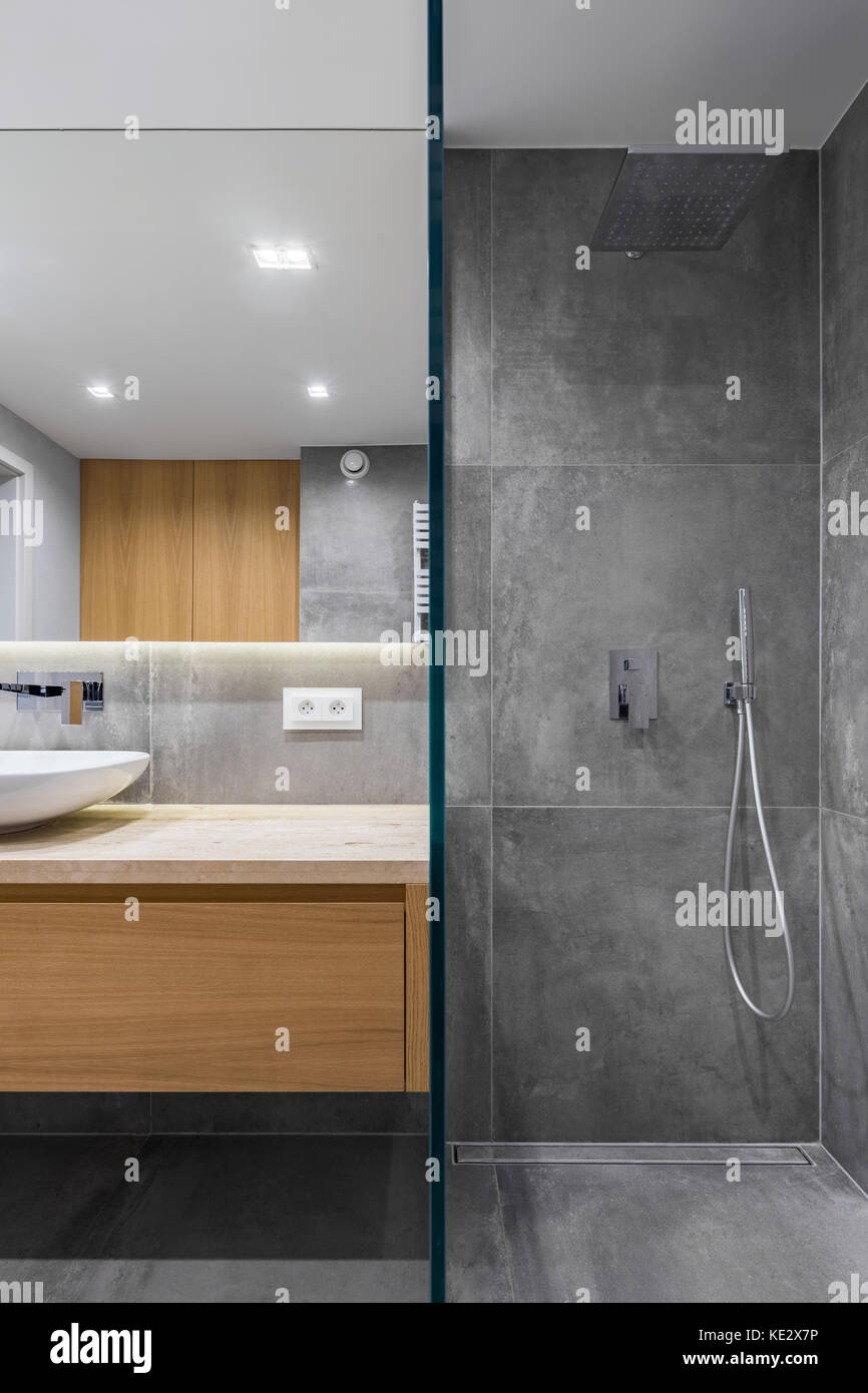 Grau Bad mit ebenerdiger Dusche, Spiegel und Arbeitsplatte Becken Stockfoto