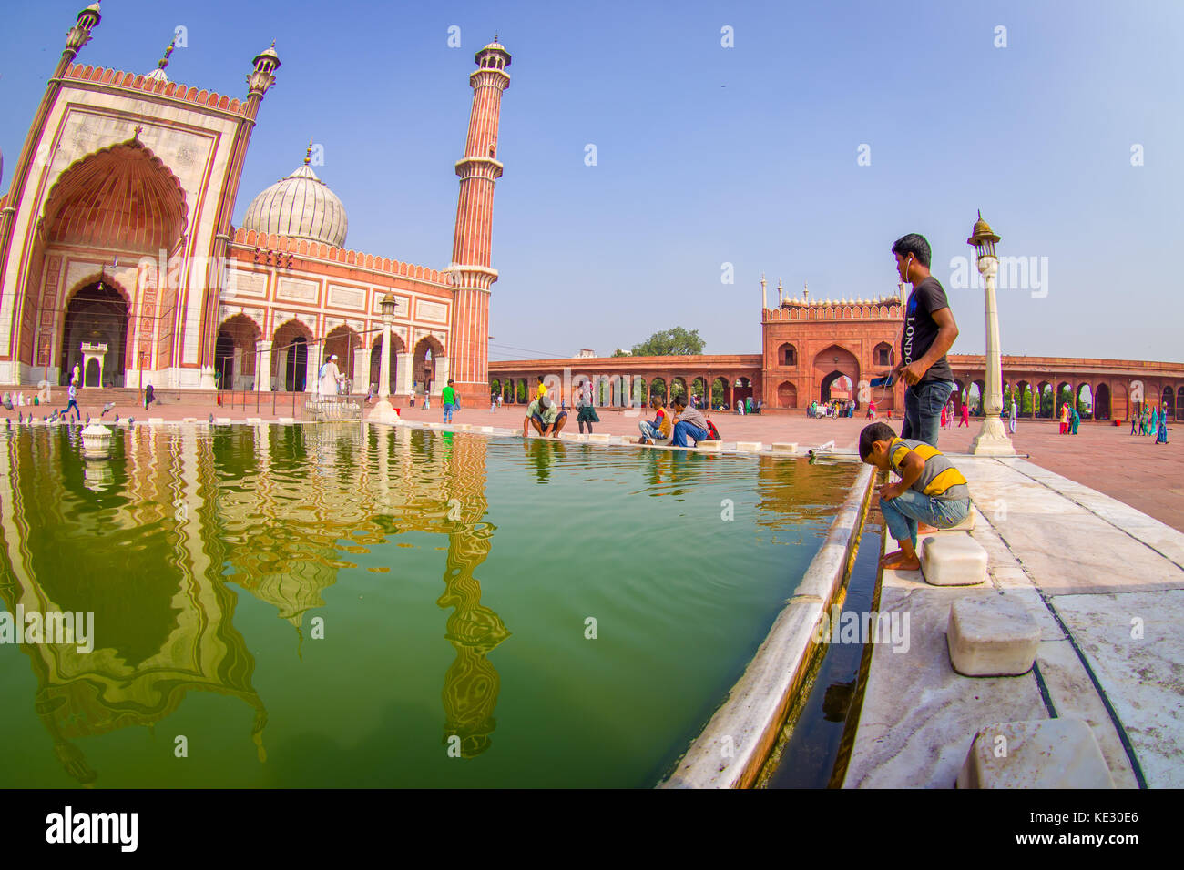 Delhi, Indien - 27. September 2017: Clos eup von unbekannten Menschen zu Fuß in der Nähe des künstlichen Teich vor einem wunderschönen Jama Masjid Tempel, das ist die größte Moschee in Indien Delhi, Indien, Fischaugen-Effekt Stockfoto
